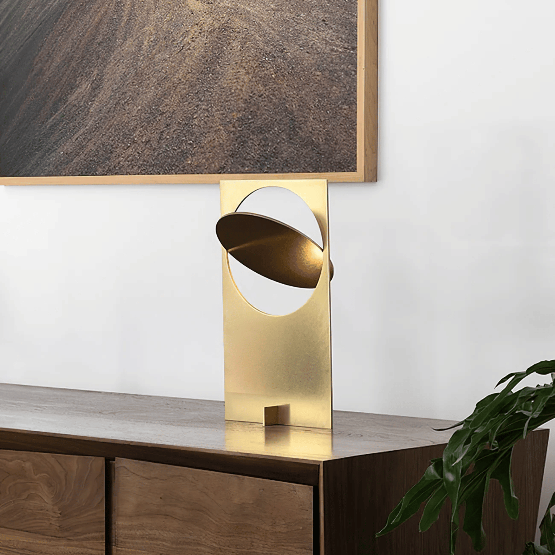 Gold table lamp on a wooden surface with a neutral background