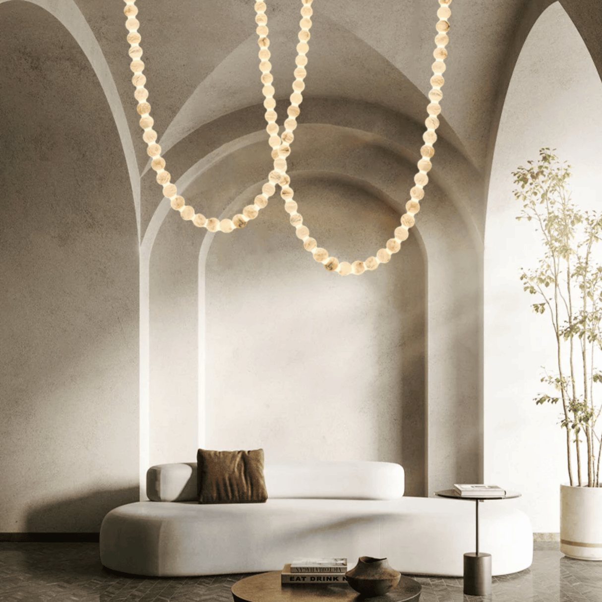 Modern living room with a white sofa, decorative pillows, and a hanging pearl necklace-like light fixture.