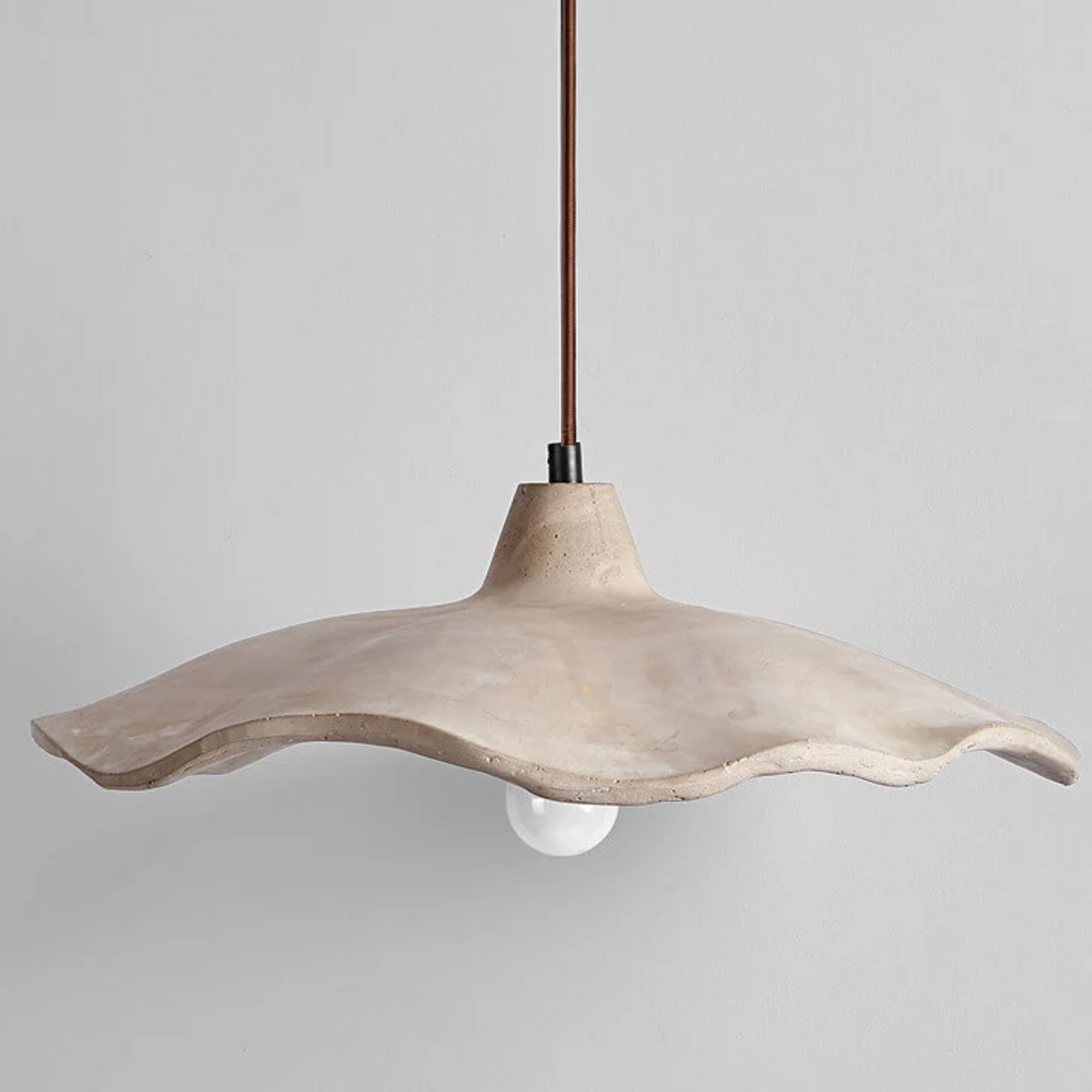 Concrete pendant light with a wavy design on a gray background