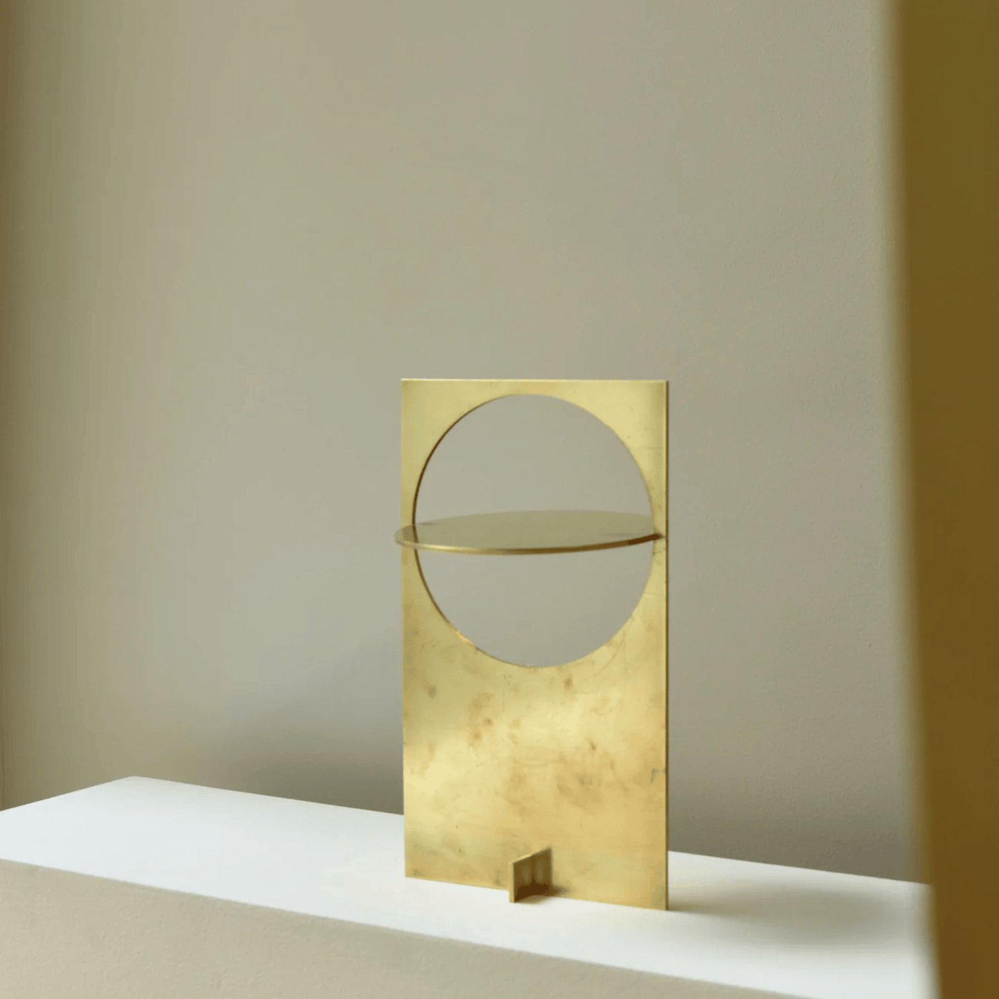 Gold decorative object with circular design on a neutral background