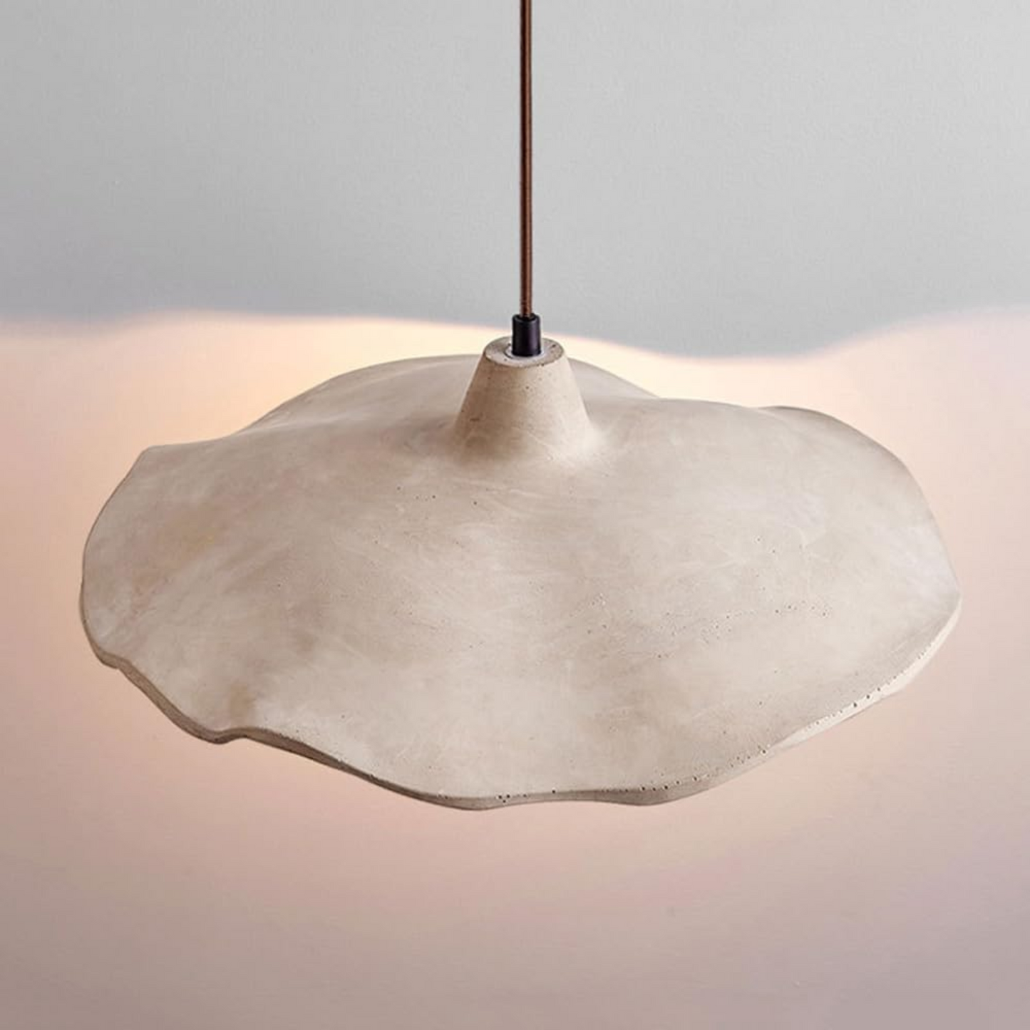 Concrete pendant light with a soft glow on a neutral background