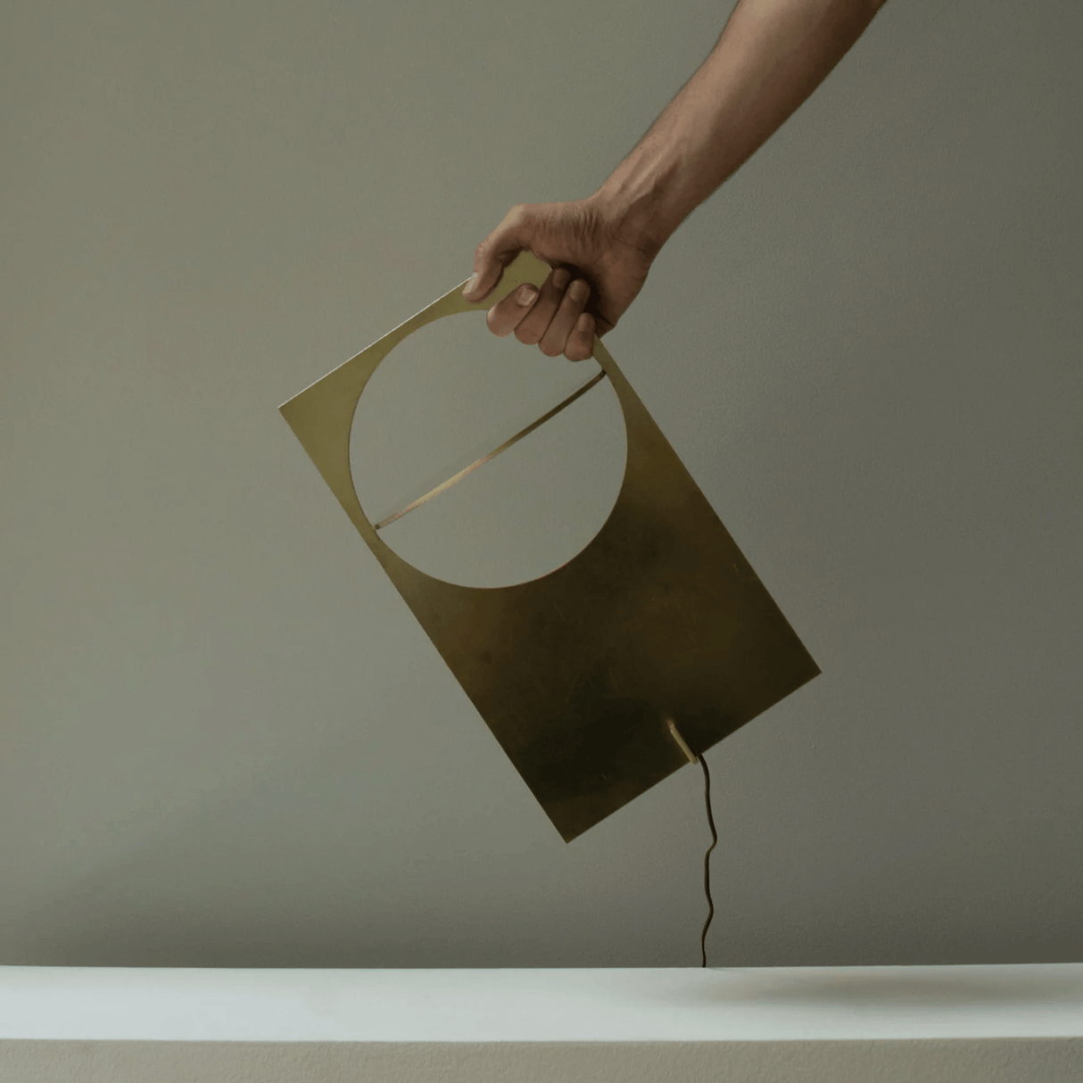 Hand holding a geometric lamp against a plain background