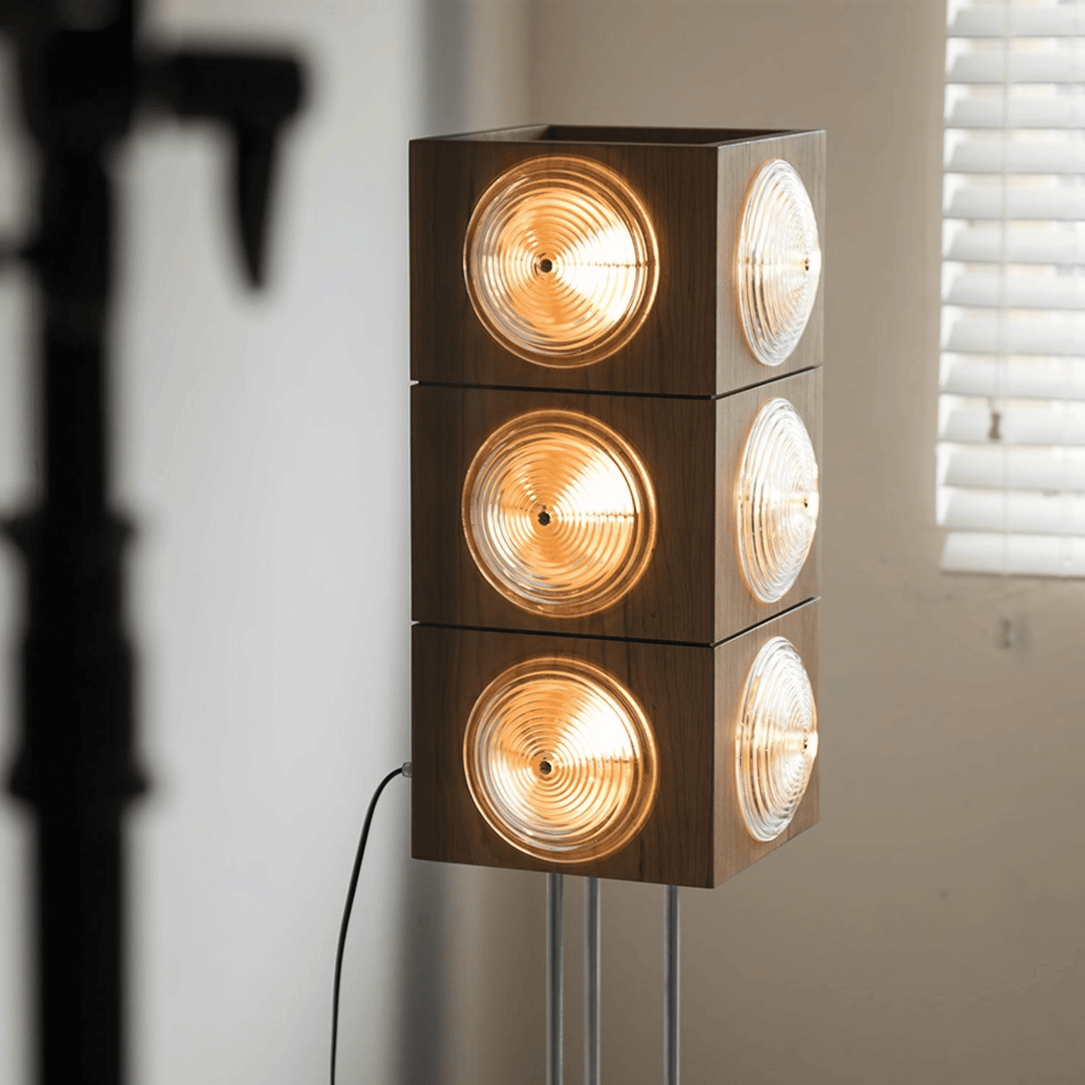 Modern floor lamp with four cylindrical lights stacked vertically against a neutral wall.