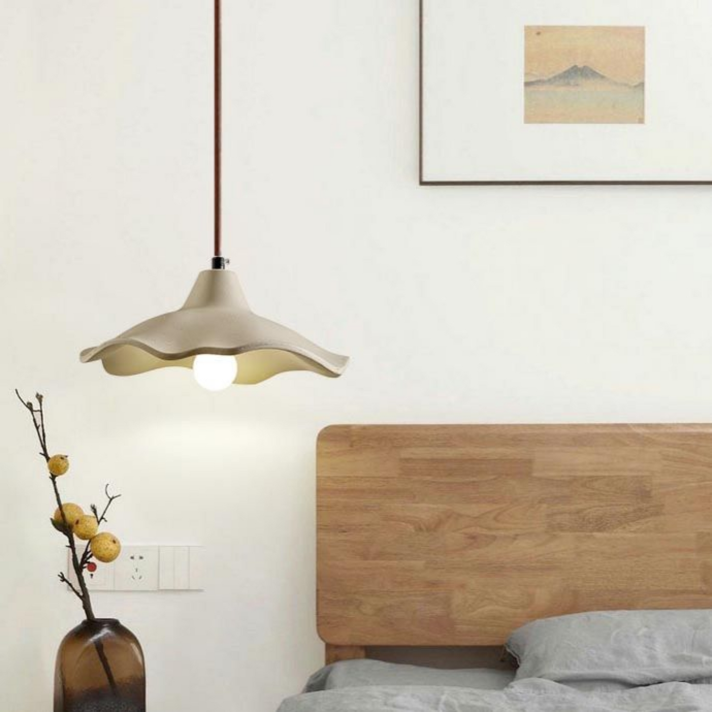 Modern pendant light hanging above a bed in a bedroom setting.