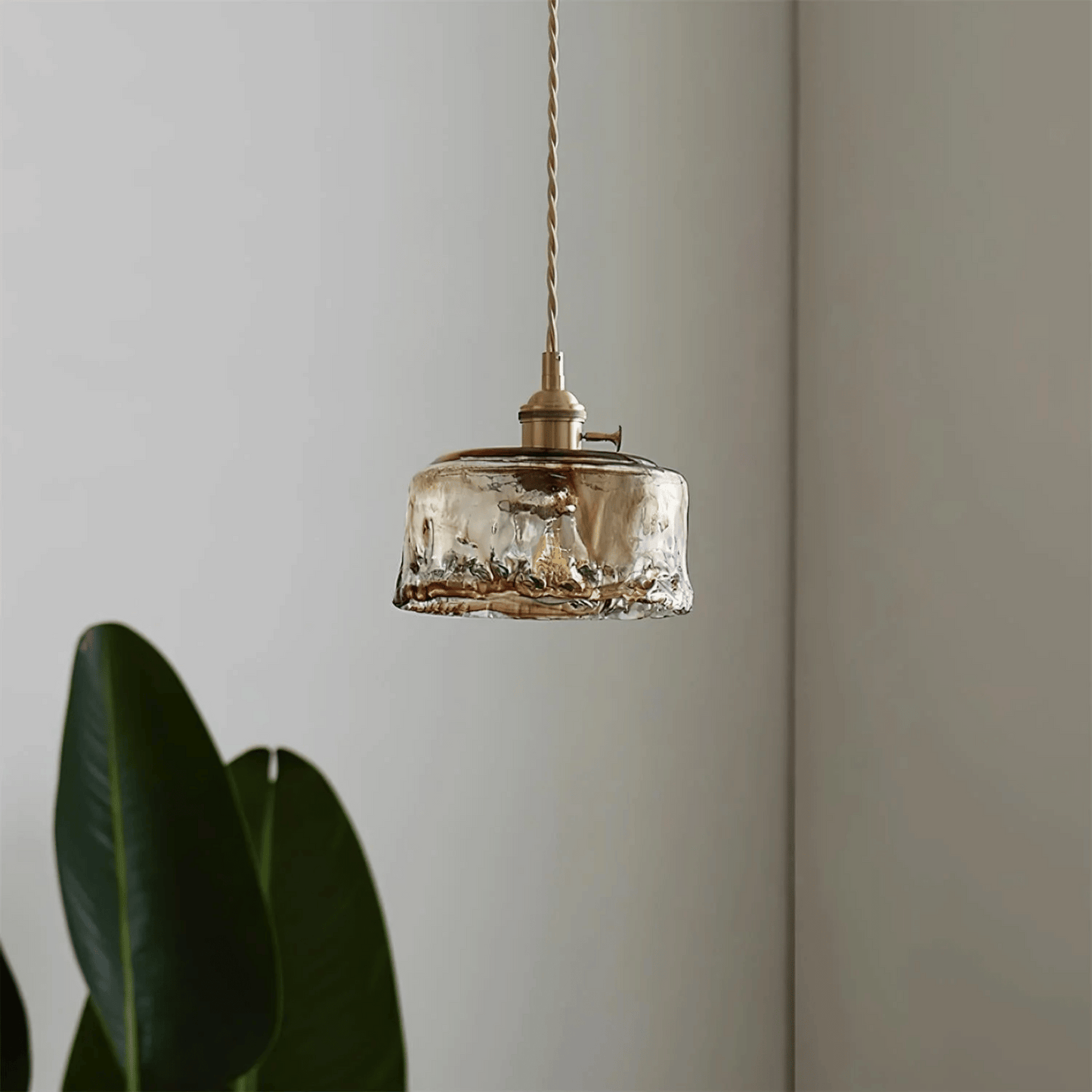 Vintage-style pendant light with glass shade and brass fixture against a neutral wall.