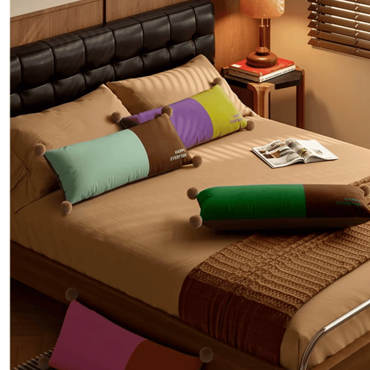 Bed with colorful pillows and a magazine on a wooden nightstand.