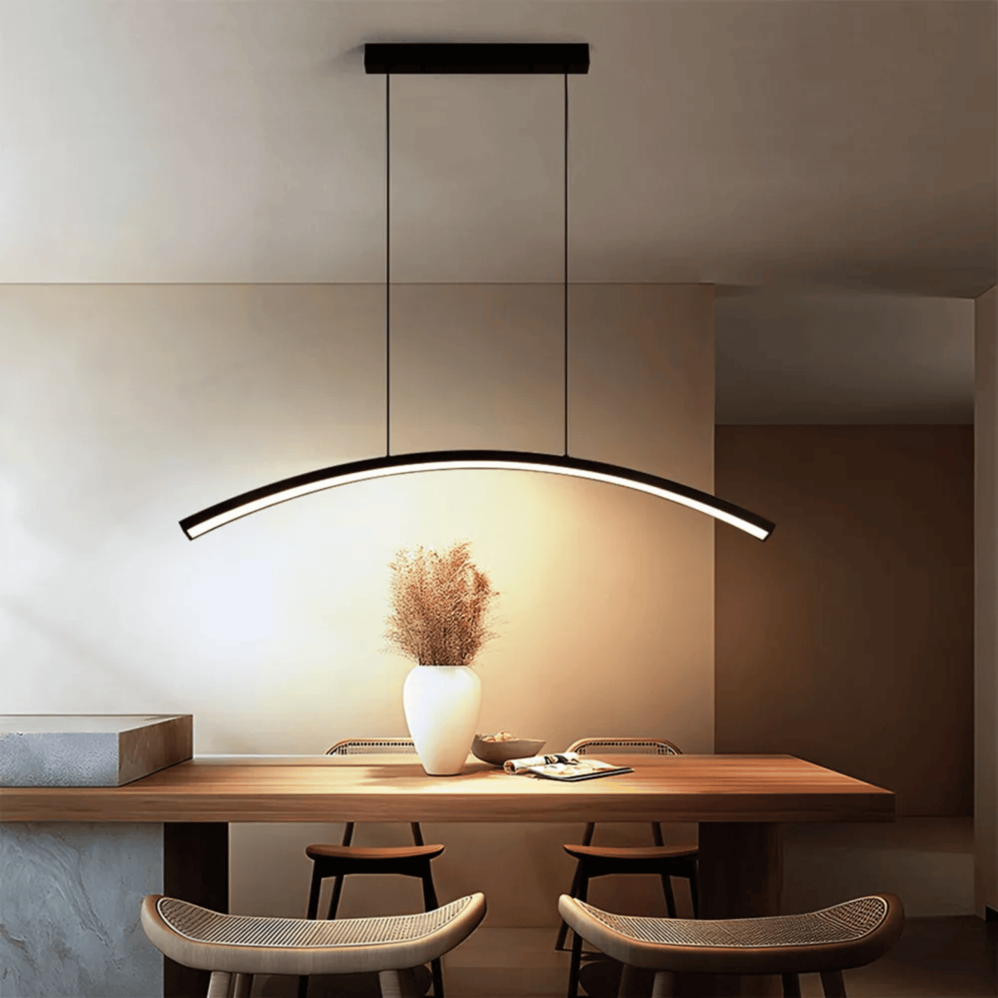 Modern pendant light hanging above a dining table with chairs in a minimalistic setting.