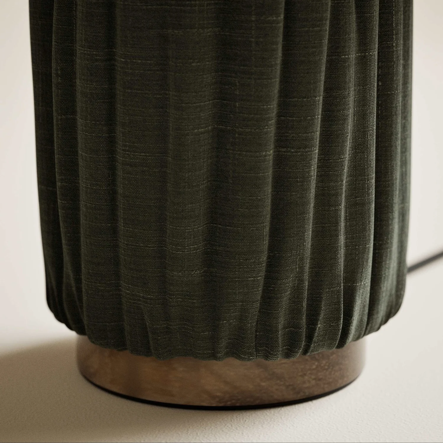 Close-up of a pleated green fabric object on a neutral background