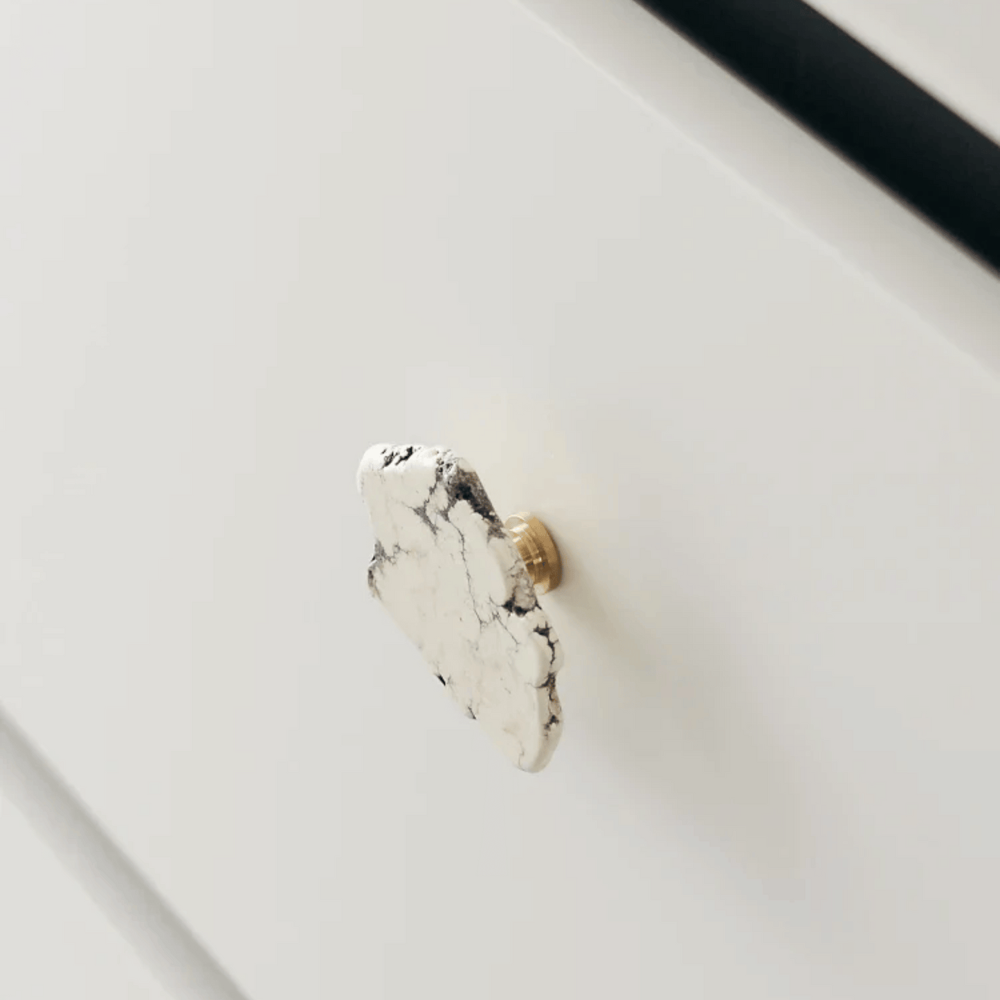Marble-textured cabinet knob on a white drawer