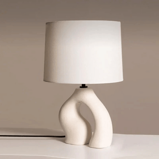 Table lamp with a white shade and unique base on a neutral background