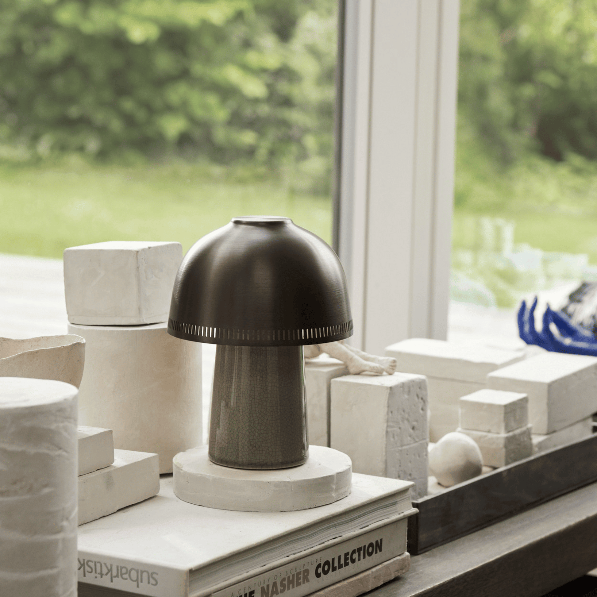 Decorative lamp on a surface with books and architectural models in the background