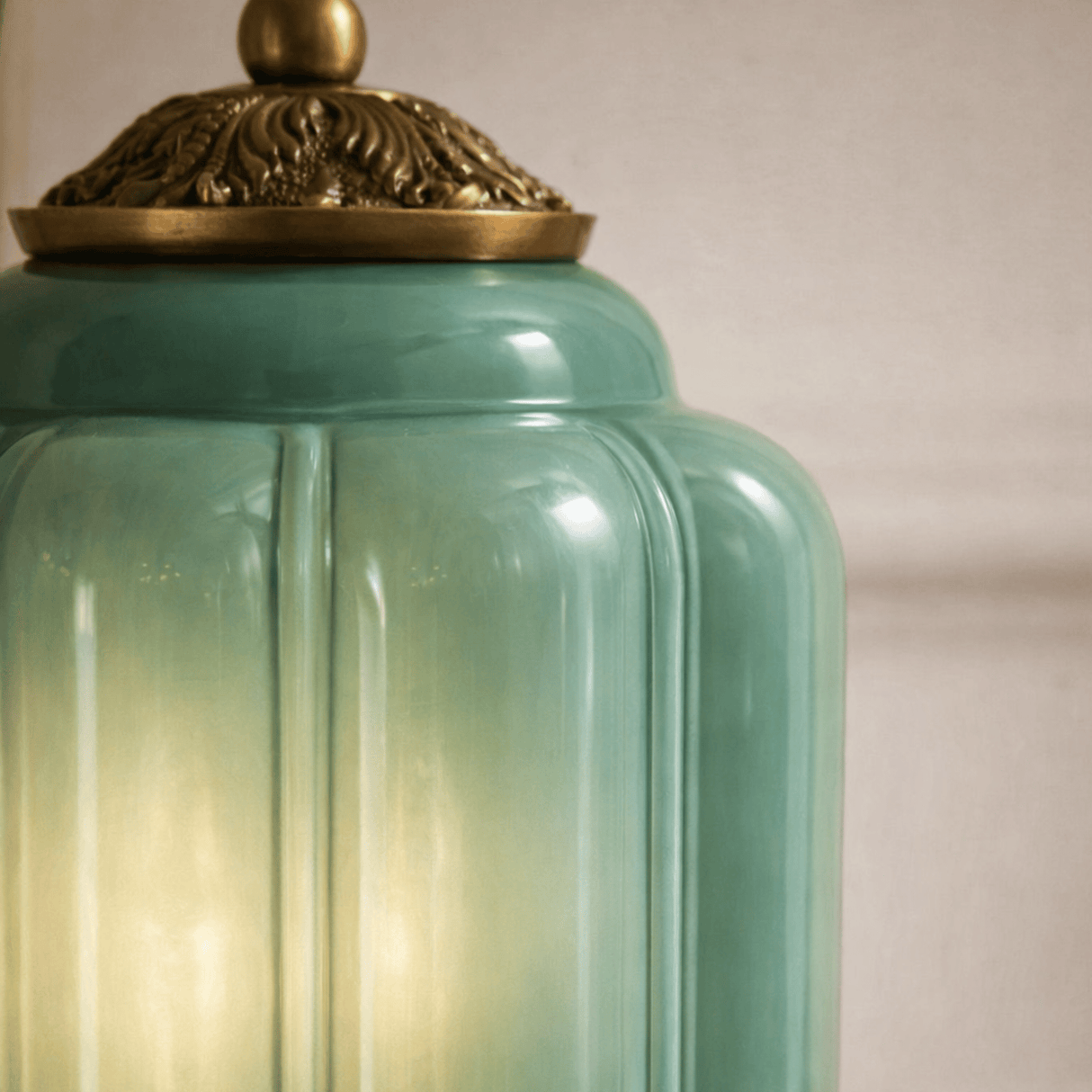 Teal glass jar with a gold lid on a neutral background