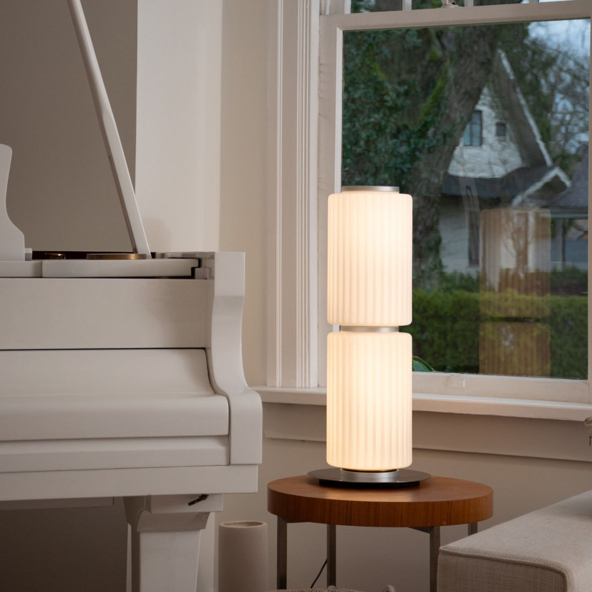 Warm-lit ribbed-glass lamp on a glass dining table in a dark interior.