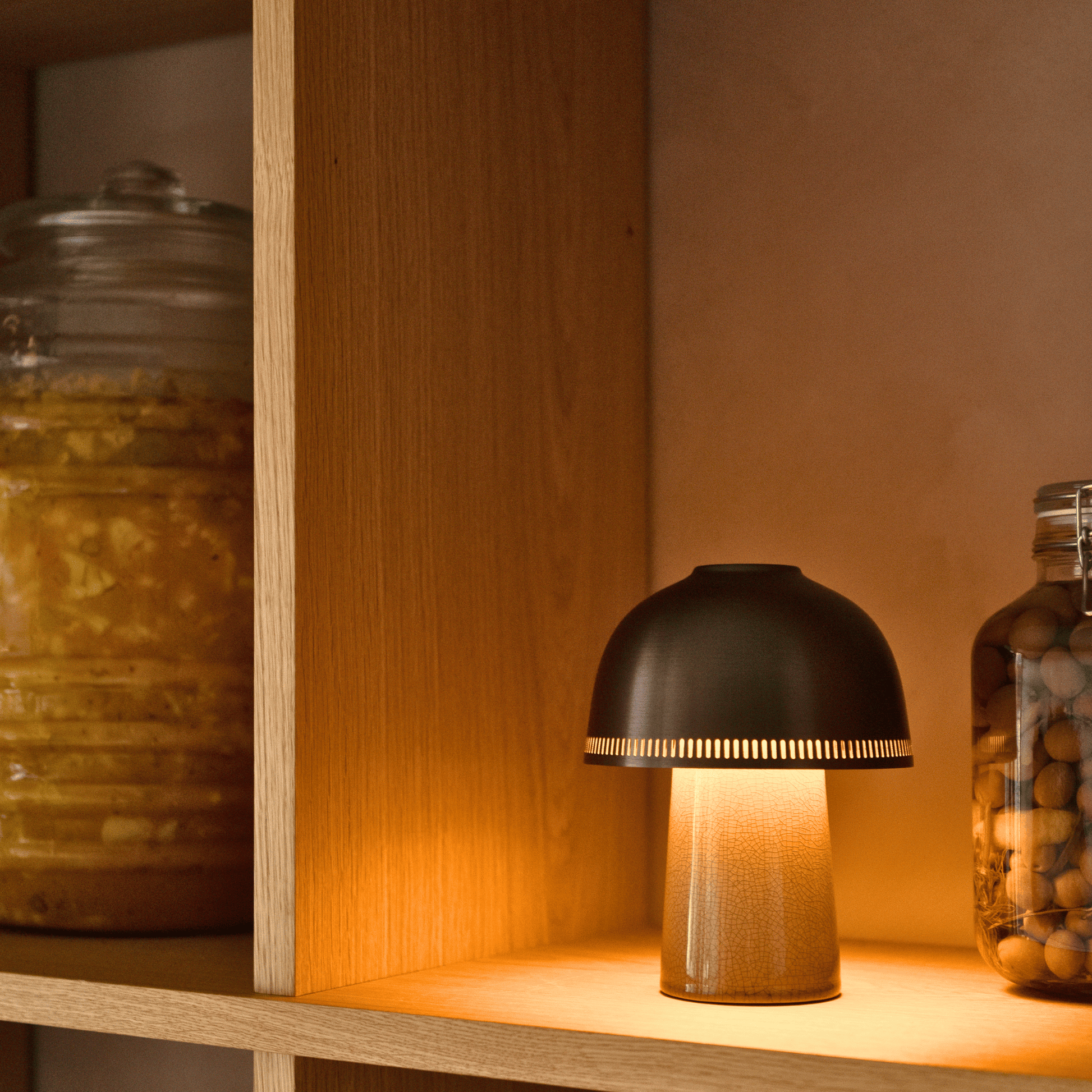 Small lamp on a wooden shelf with jars on either side