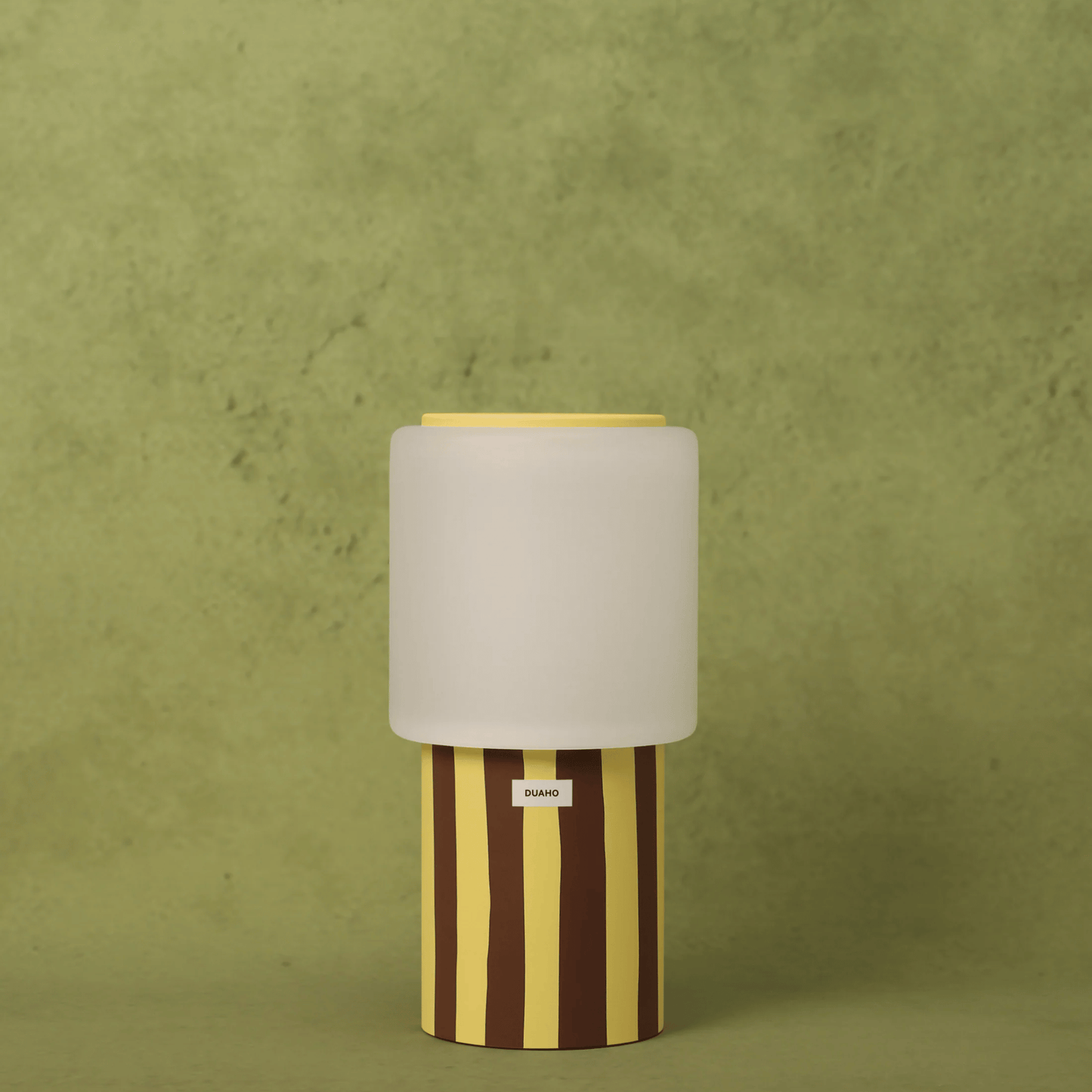 Table lamp with striped base and beige shade on a green background