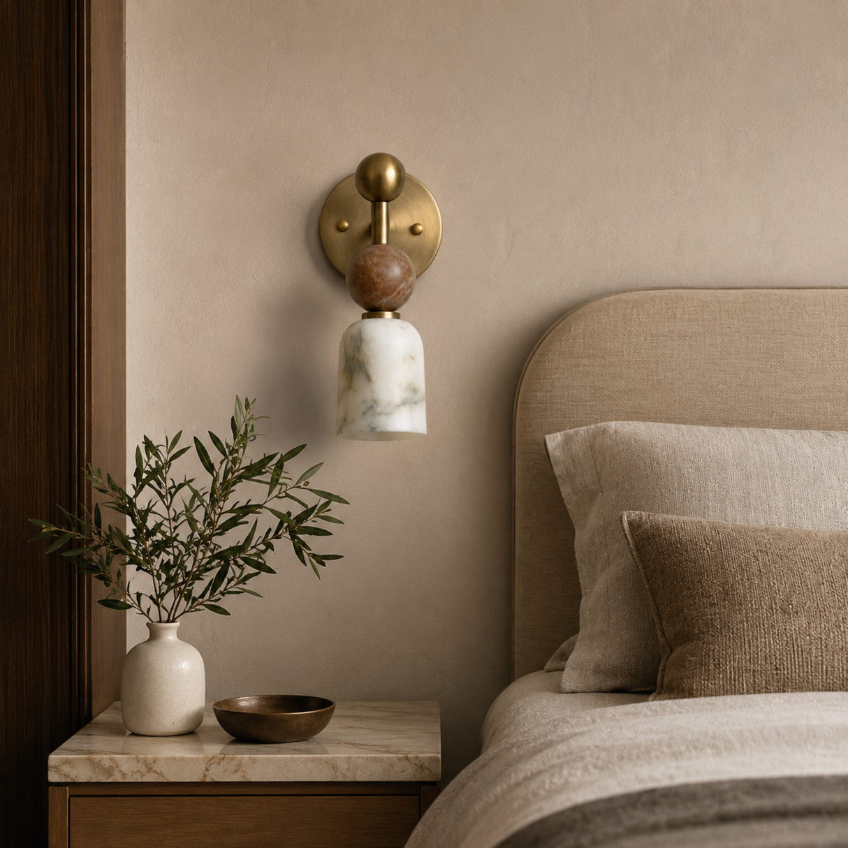 Decorative wall sconce above a bed with pillows and a plant on a nightstand.