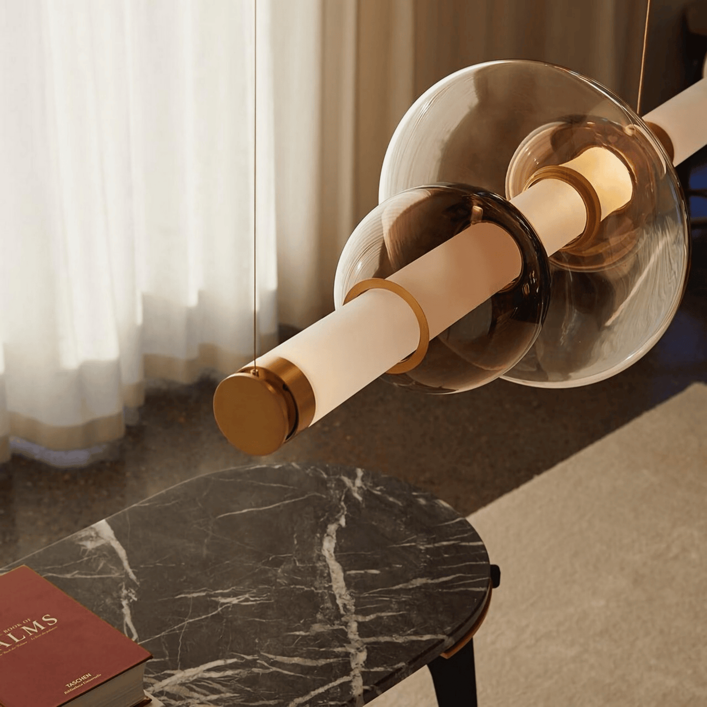 Close-up of a gold and bronze door handle on a marble surface with curtains in the background.
