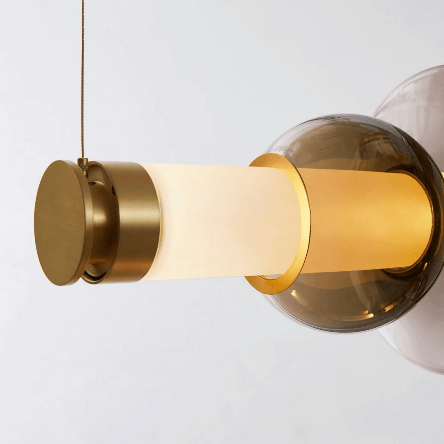 Modern pendant light with gold and glass design on a white background