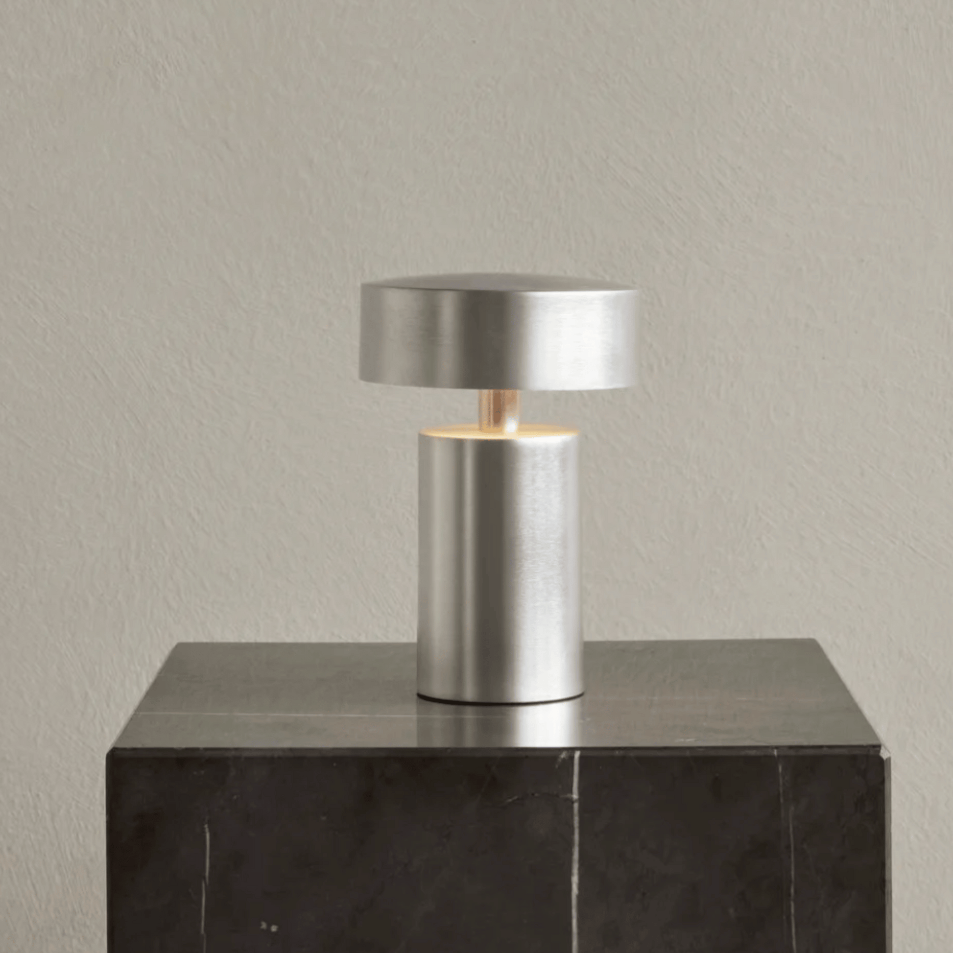 Modern silver table lamp on a dark surface with a neutral background