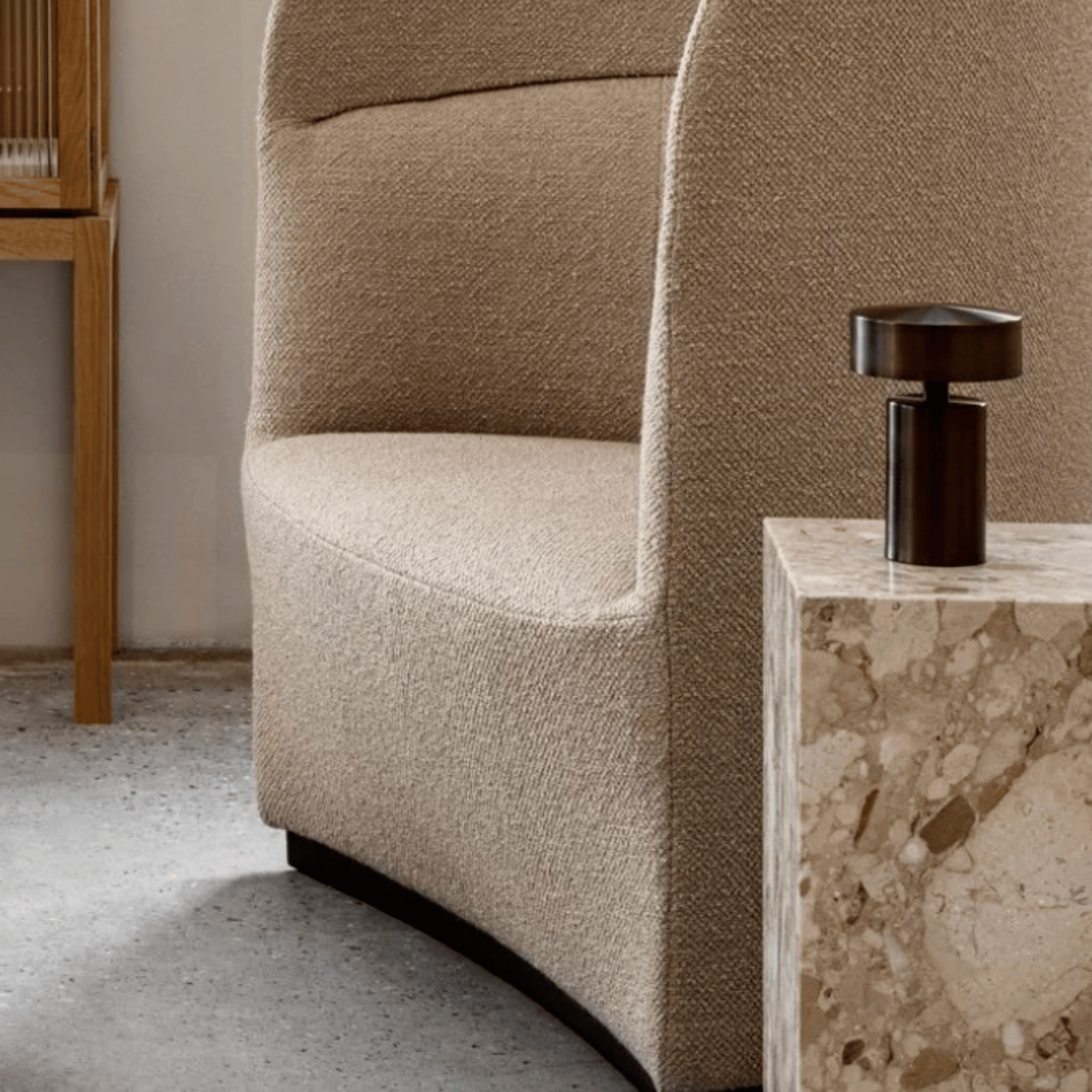 Beige armchair with a marble side table and decorative object in a room setting.