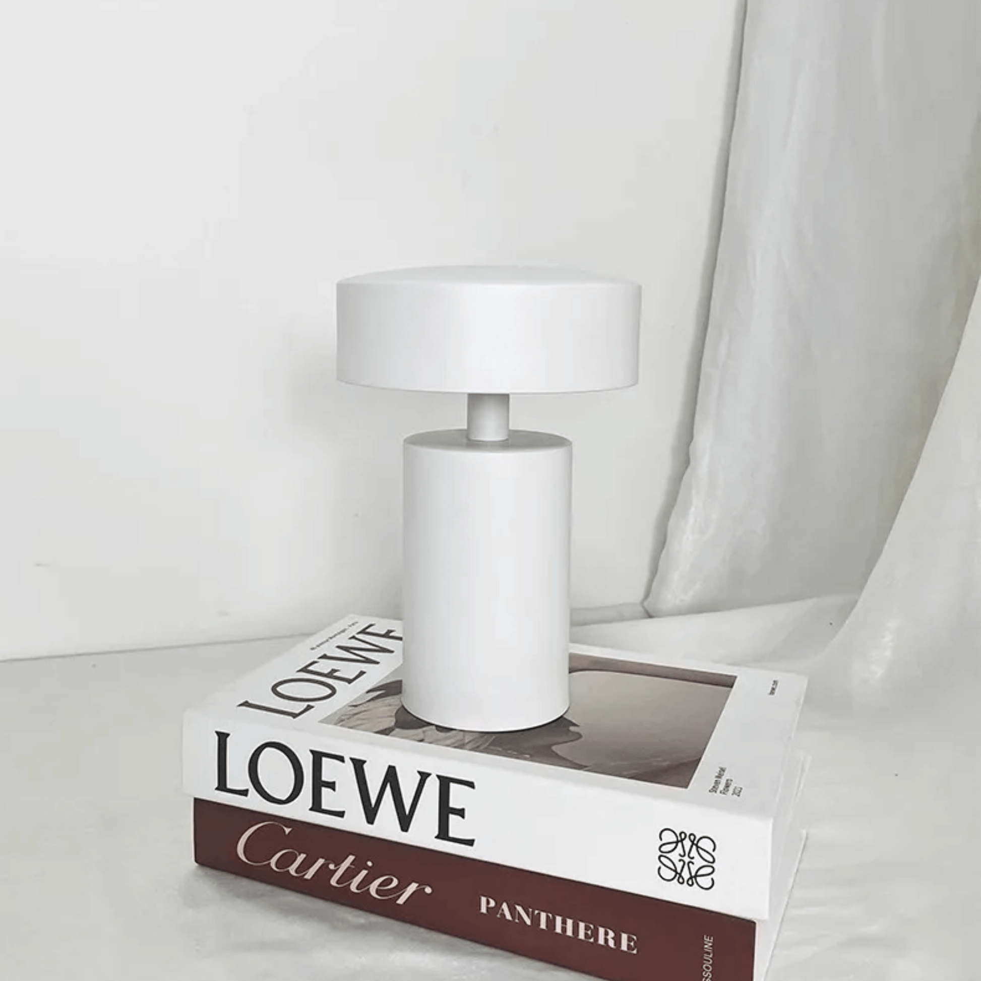 White lamp on a Loewe box with a white curtain in the background