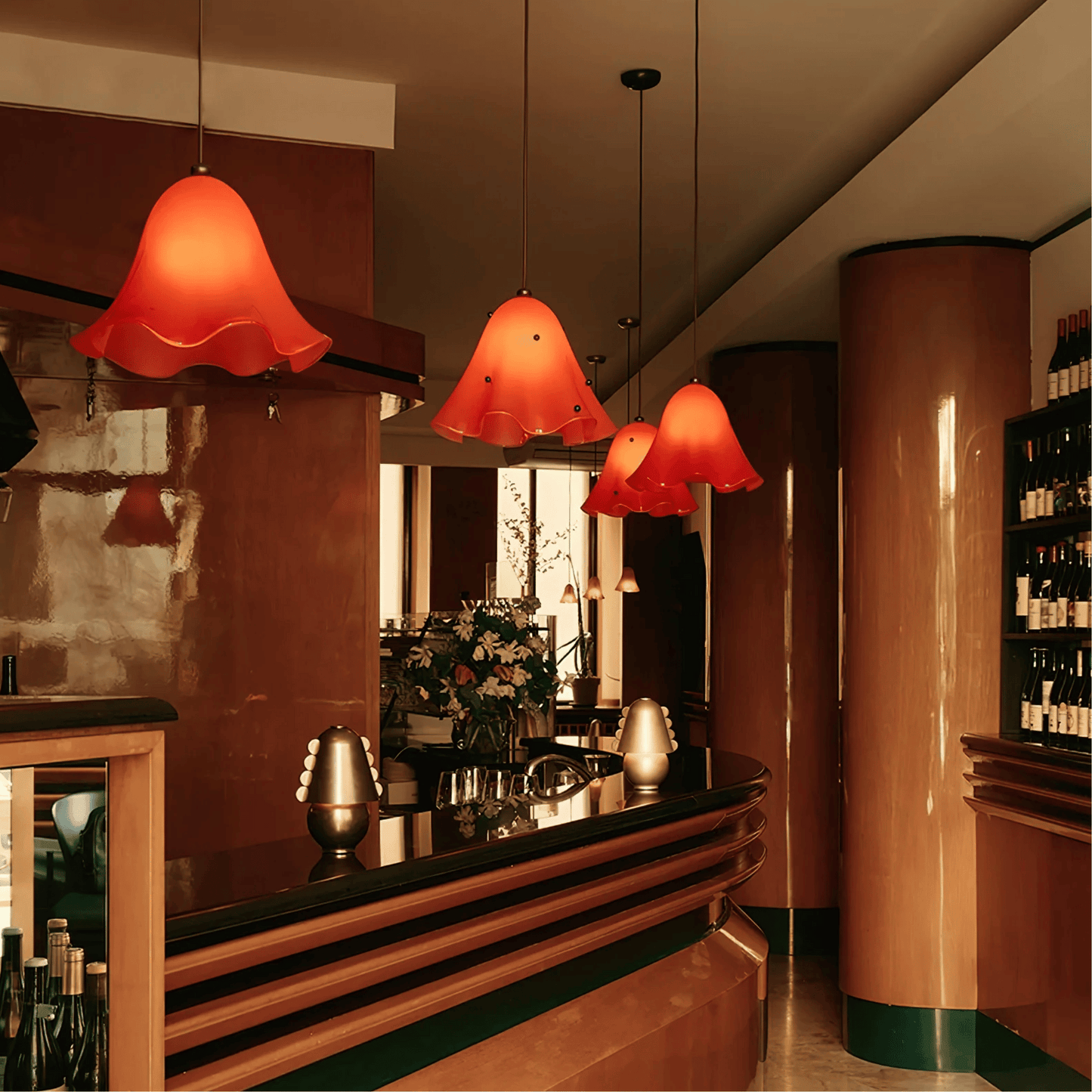 Bar area with red pendant lights, floral arrangement, and bottles.