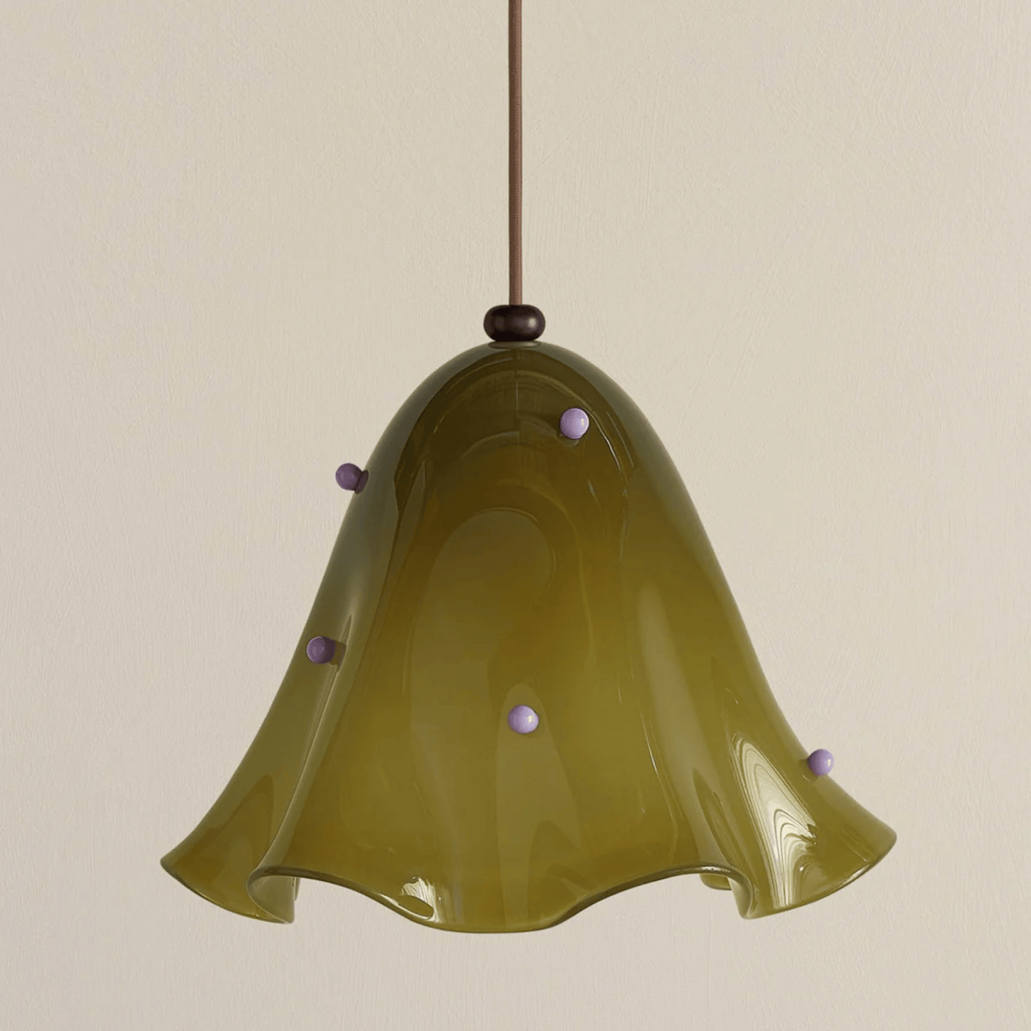 Green glass pendant light with decorative beads on a beige background