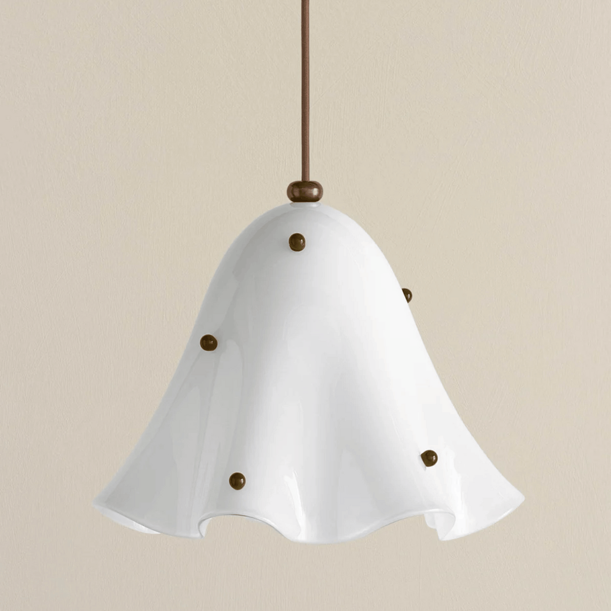 White pendant light with brass accents on a beige background