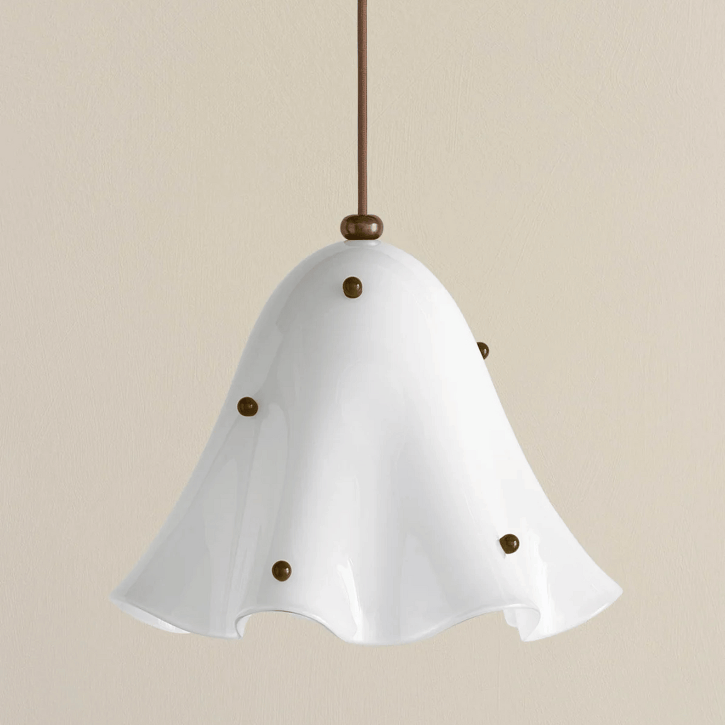 White pendant light with brass accents on a beige background