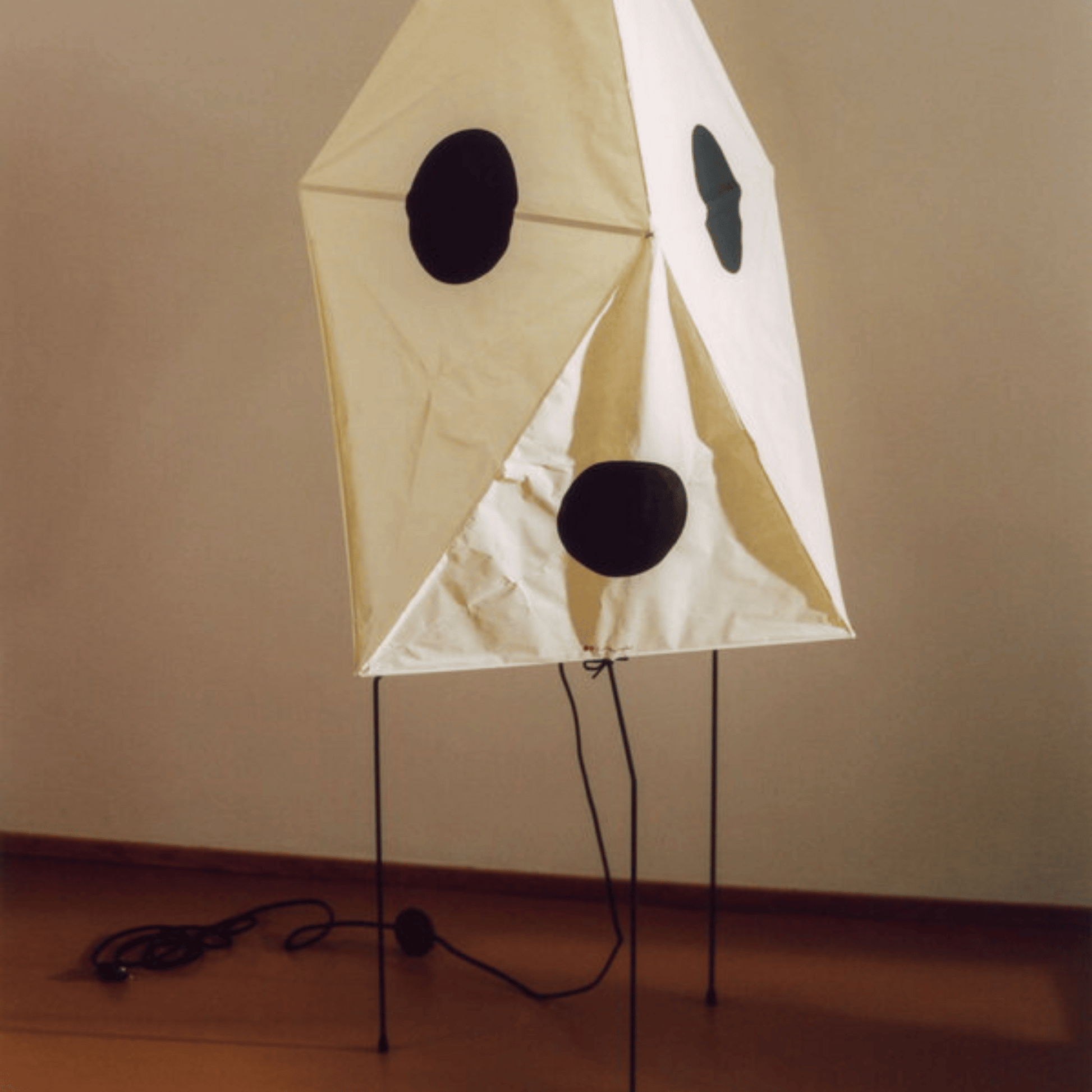Decorative lamp shaped like a ghost with black eyes and mouth on a beige background