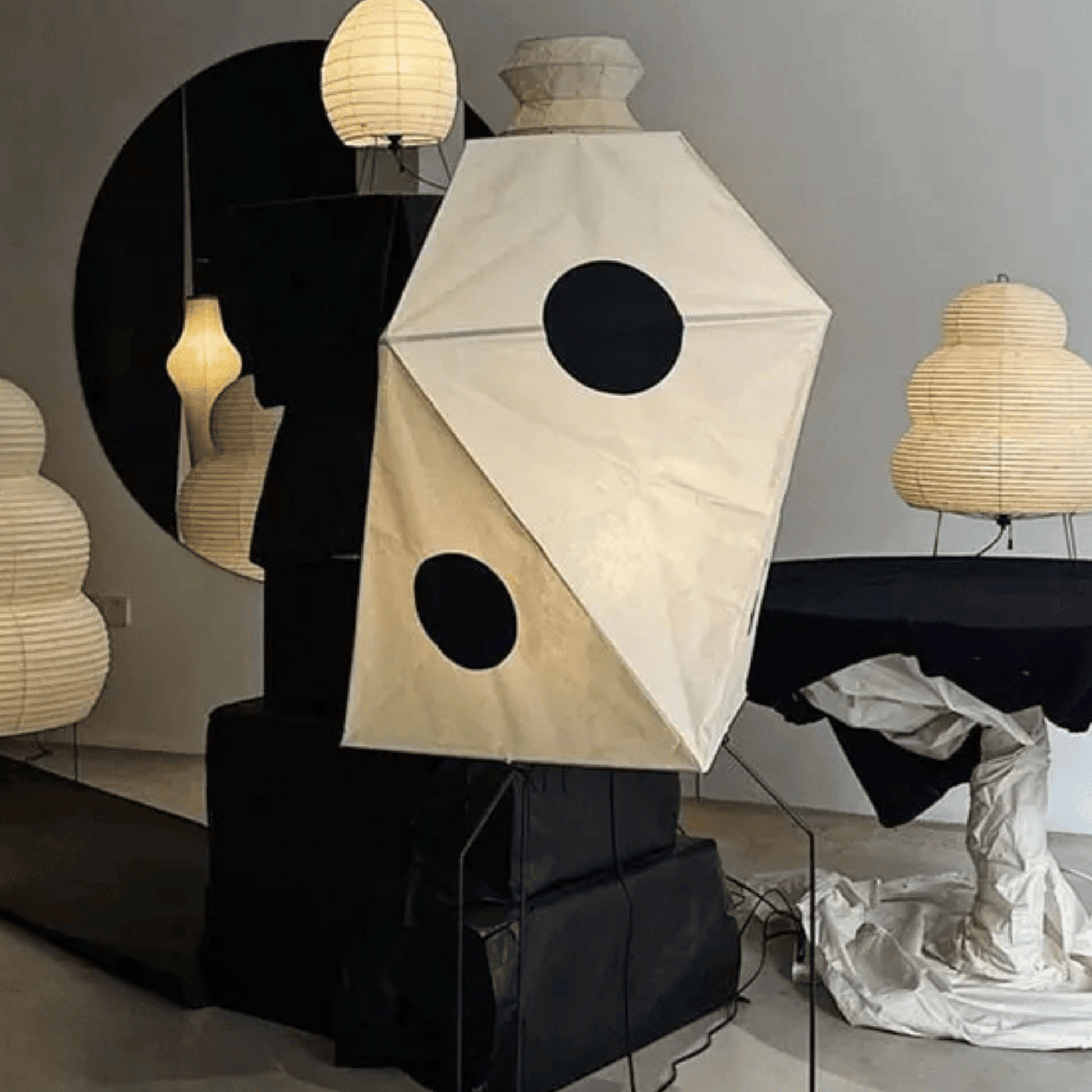 Geometric lamp with black circles on a stand in a room with other lamps.