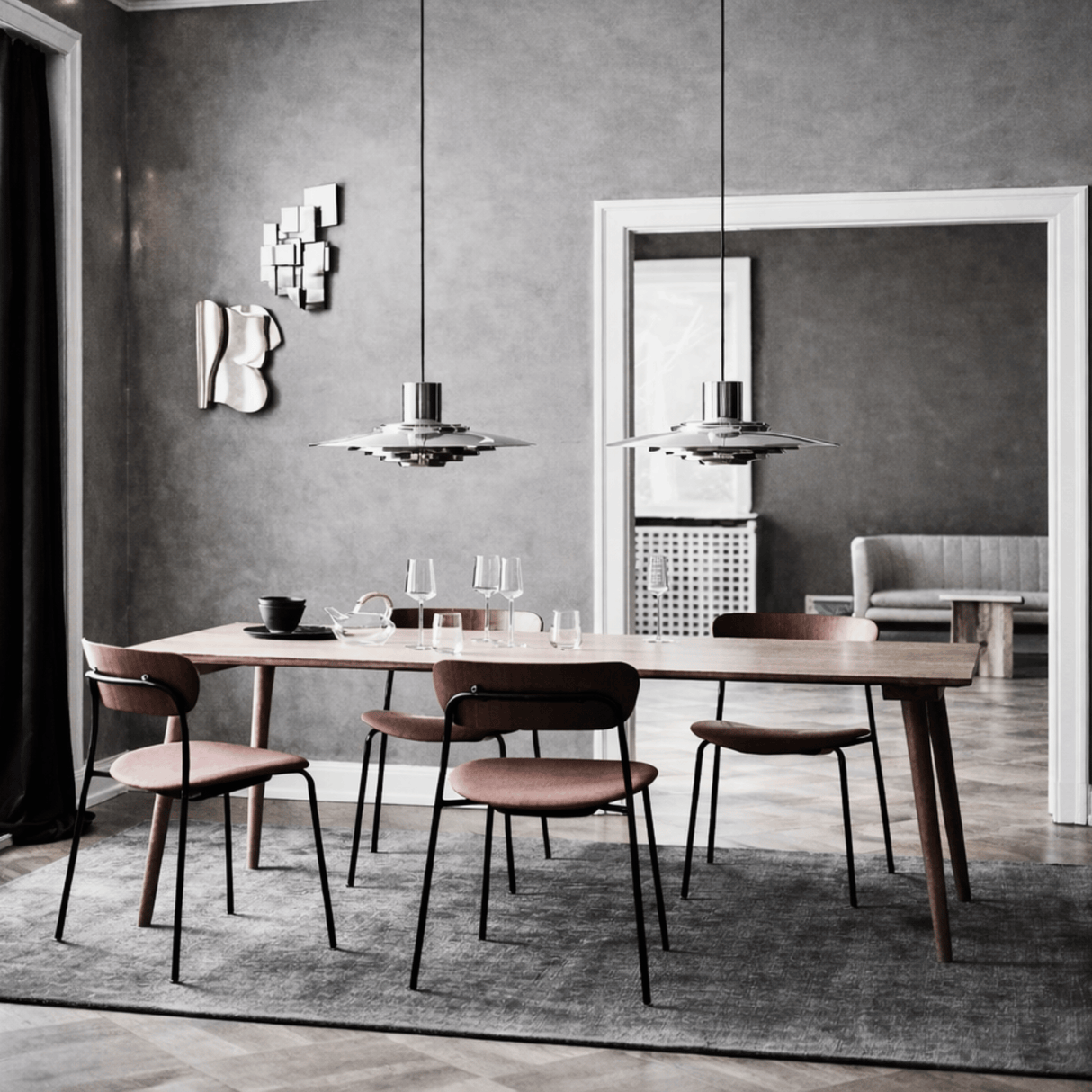 Modern dining room with wooden table and chairs against a gray wall.
