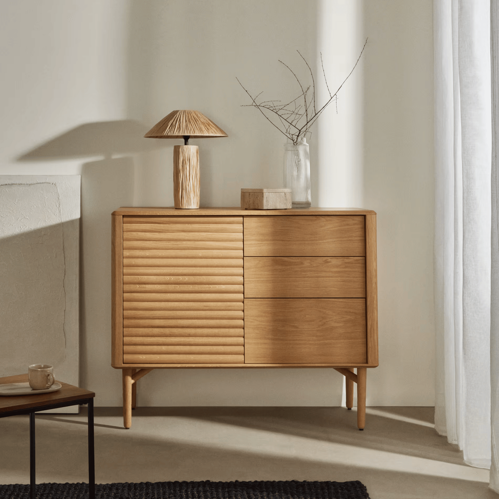 Wooden sideboard with a lamp and decorative items in a minimalistic room.