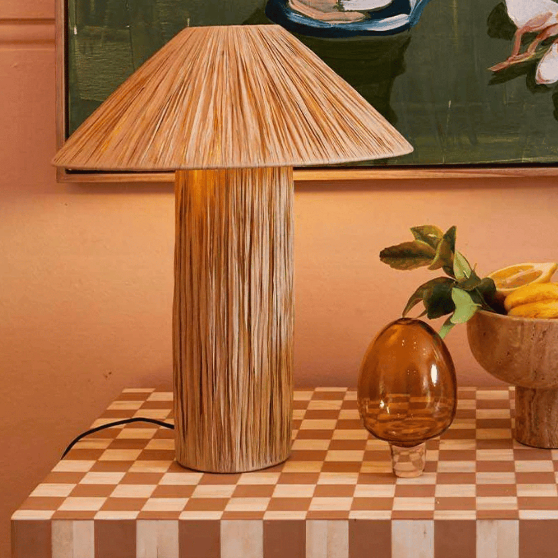 Wooden table lamp on a checkered table with a painting in the background