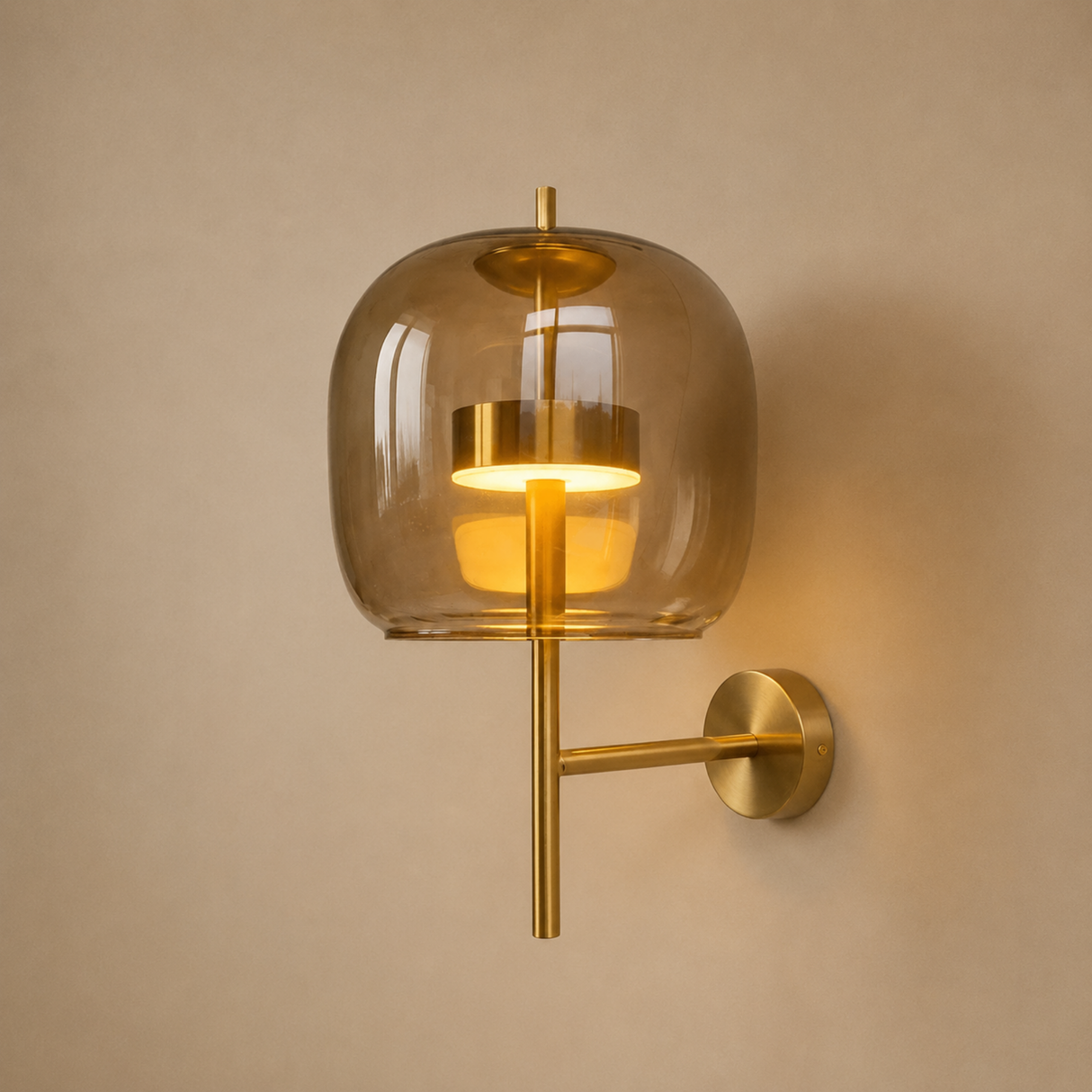 A modern wall sconce light fixture with a warm brass metal arm and a translucent amber-tinted glass dome shade, shown illuminated against a beige wall.