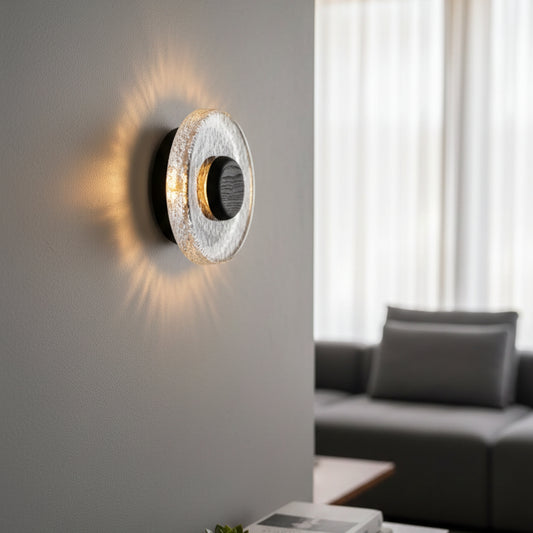 A glowing circular wall light with a stone-textured ring and dark center, installed on a light-colored wall in a modern living room.