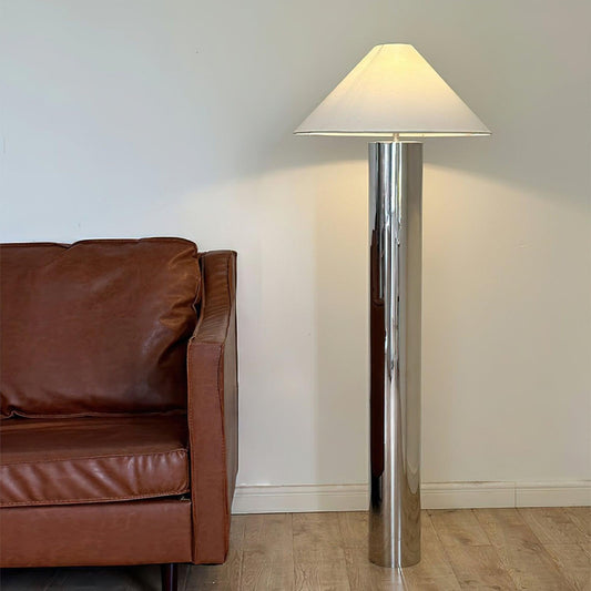 modern chrome floor lamp next to a woven cane chair and a mirrored panel on the floor