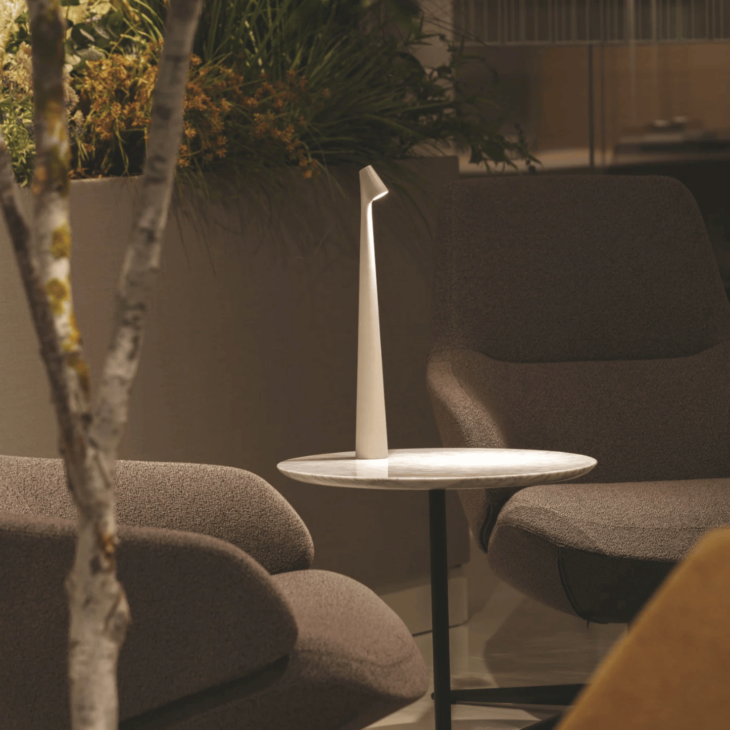 Modern outdoor seating area with a small table and chairs, featuring a plant in the background.