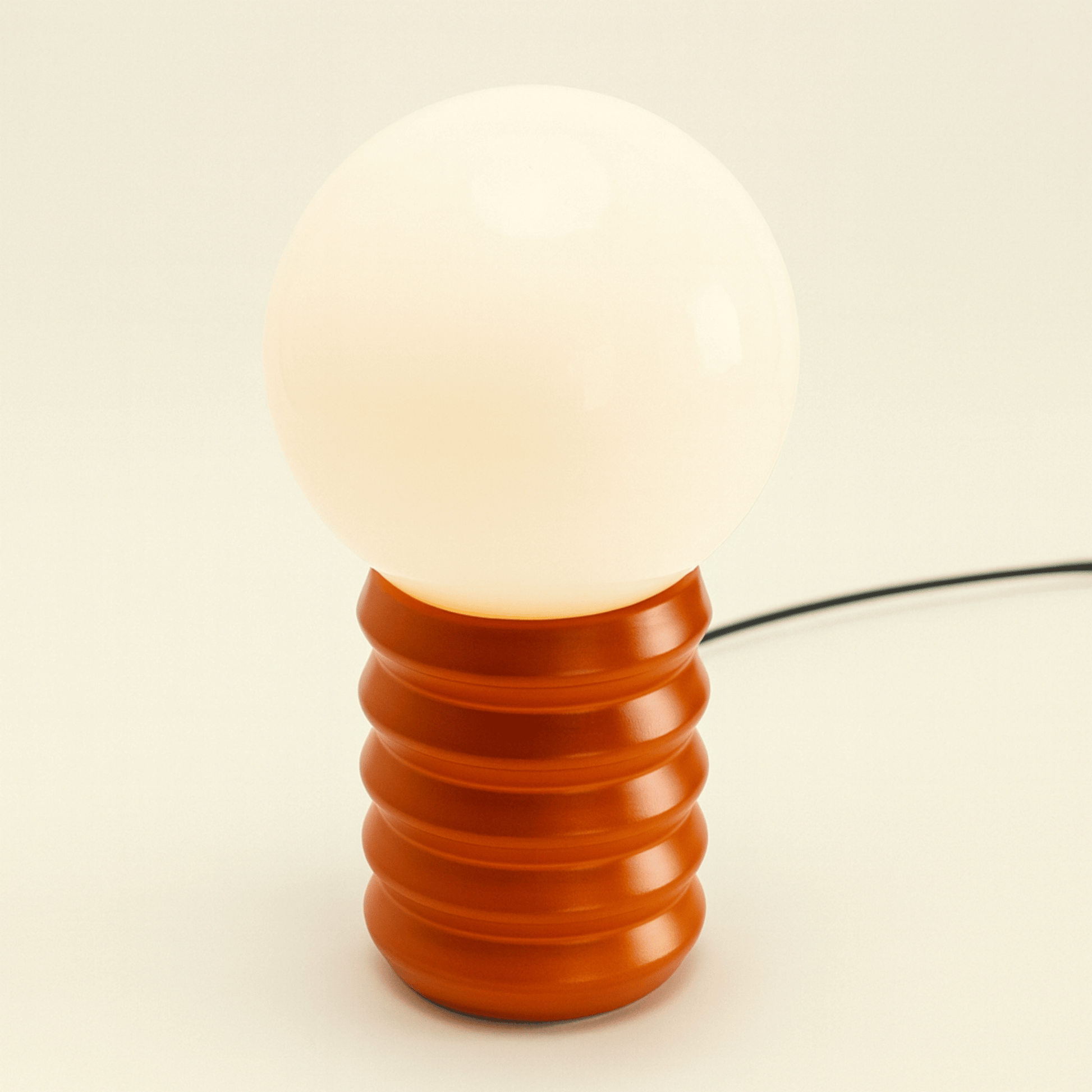 Decorative lamp with a ribbed brown base and white bulb on a beige background