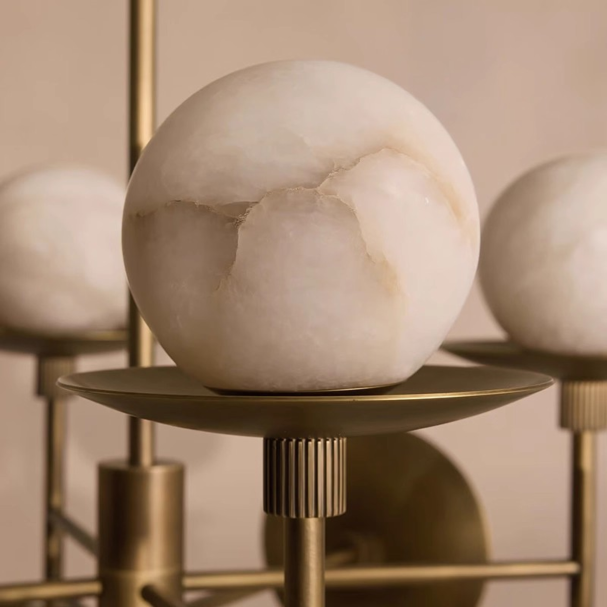 Marble sphere on a gold stand with a warm beige background