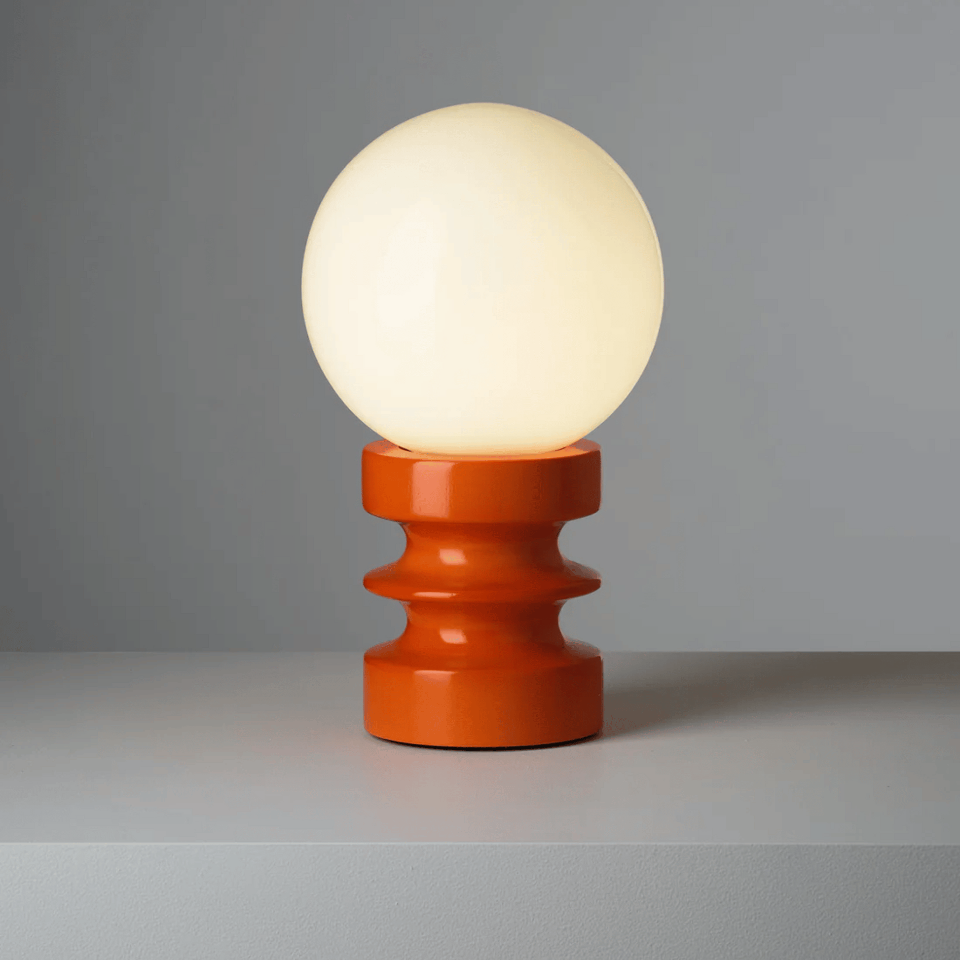 Table lamp with a round white bulb and orange base on a gray background