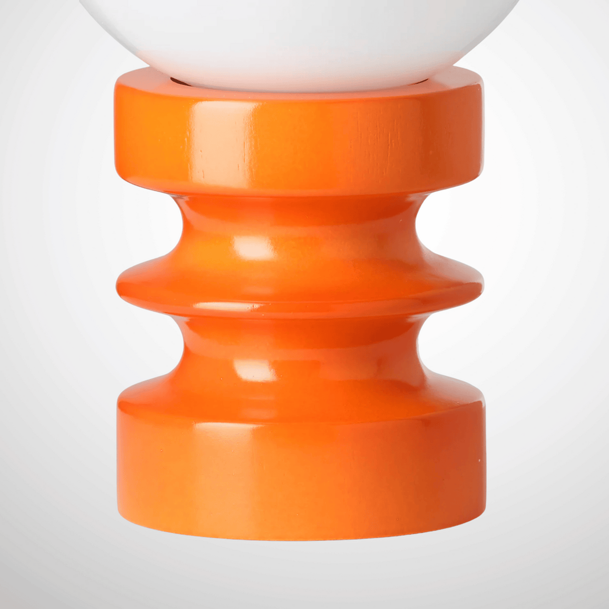 Close-up of a lamp with an orange base and white top on a light gray background