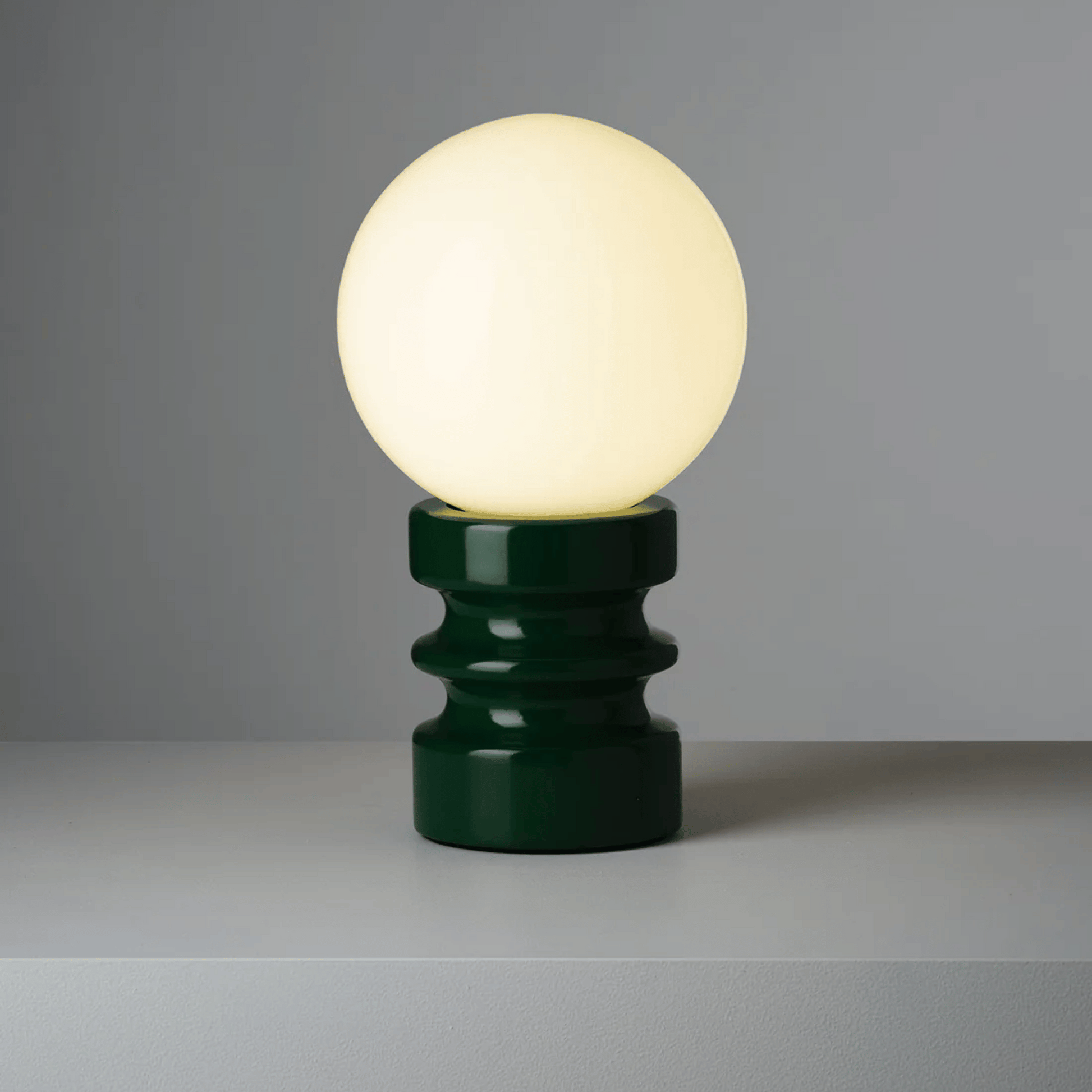 Table lamp with a green base and white bulb on a gray background