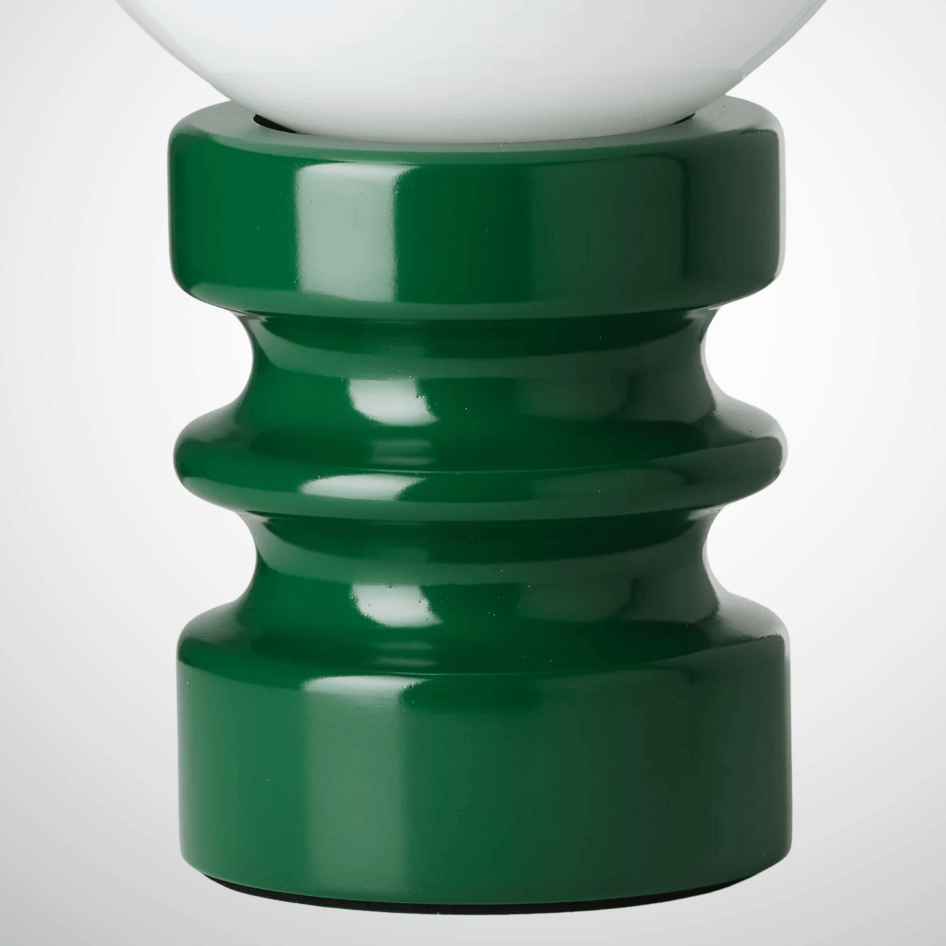 Close-up of a green lamp base with a white lampshade on a light gray background
