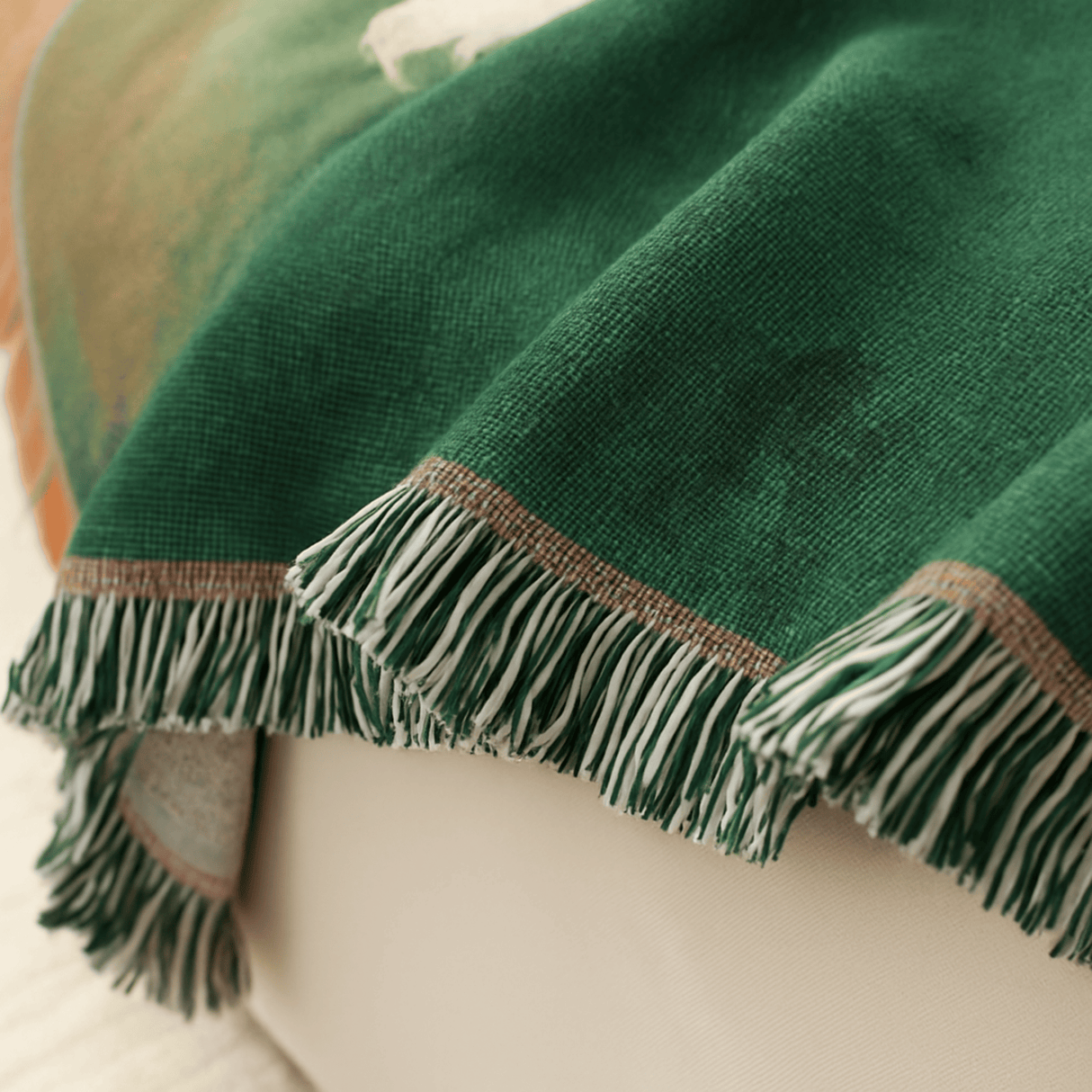 Green blanket with fringes draped over a surface
