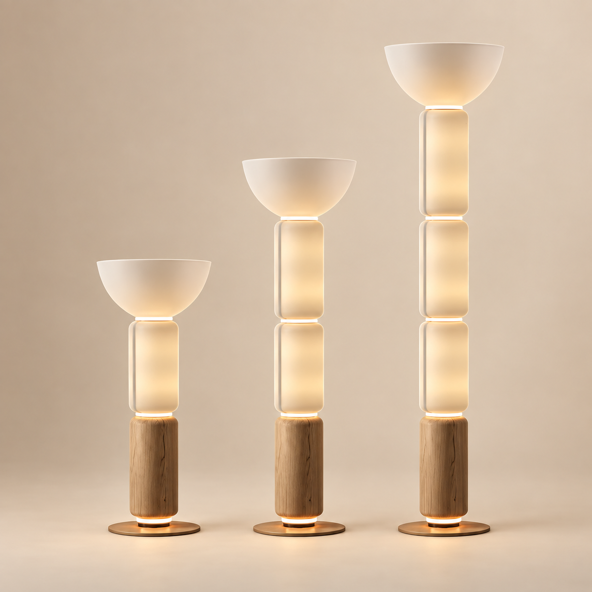 Three modern floor lamps in graduated heights, featuring frosted white bowl-shaped shades, stacked translucent cylindrical sections, light natural wood bases, and warm glowing LED lighting, set against a solid warm beige background.