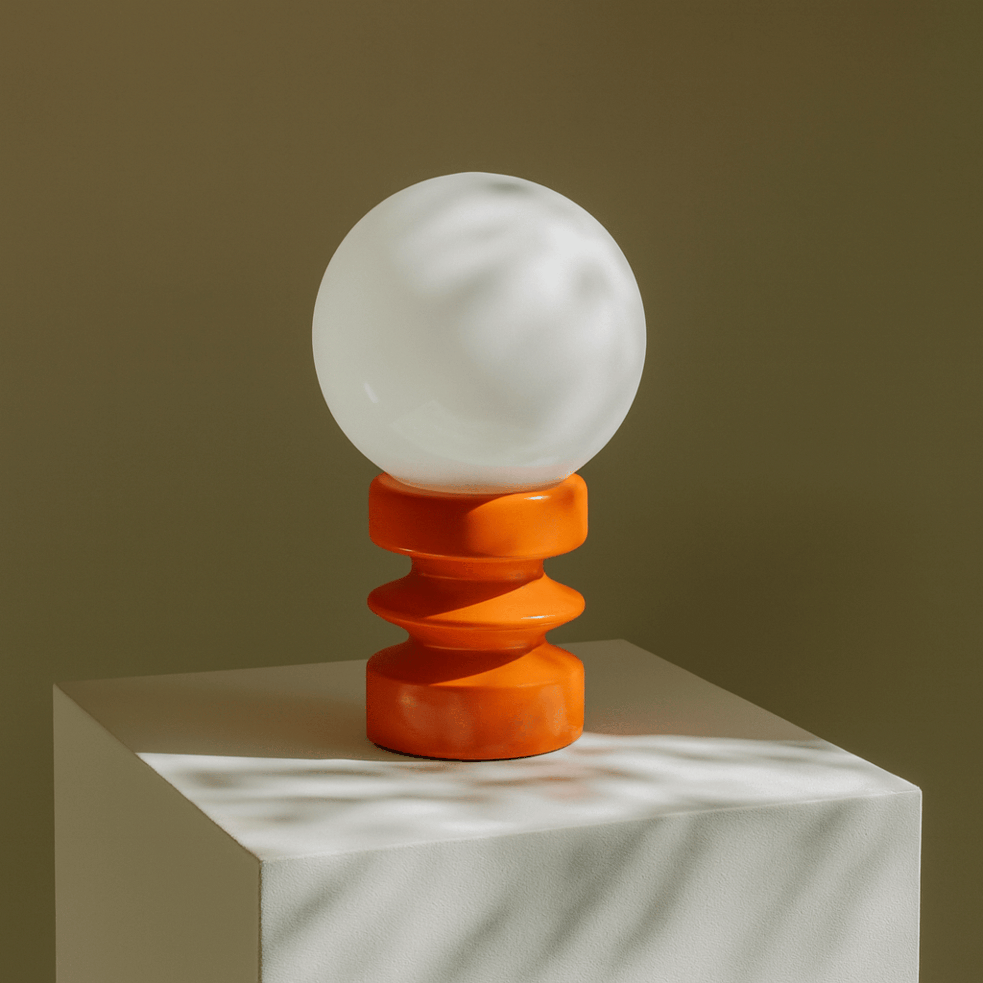 Decorative lamp with a white globe and orange base on a neutral background