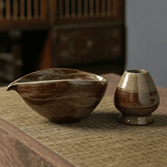 Two ceramic bowls with brown and beige glaze on a textured surface.