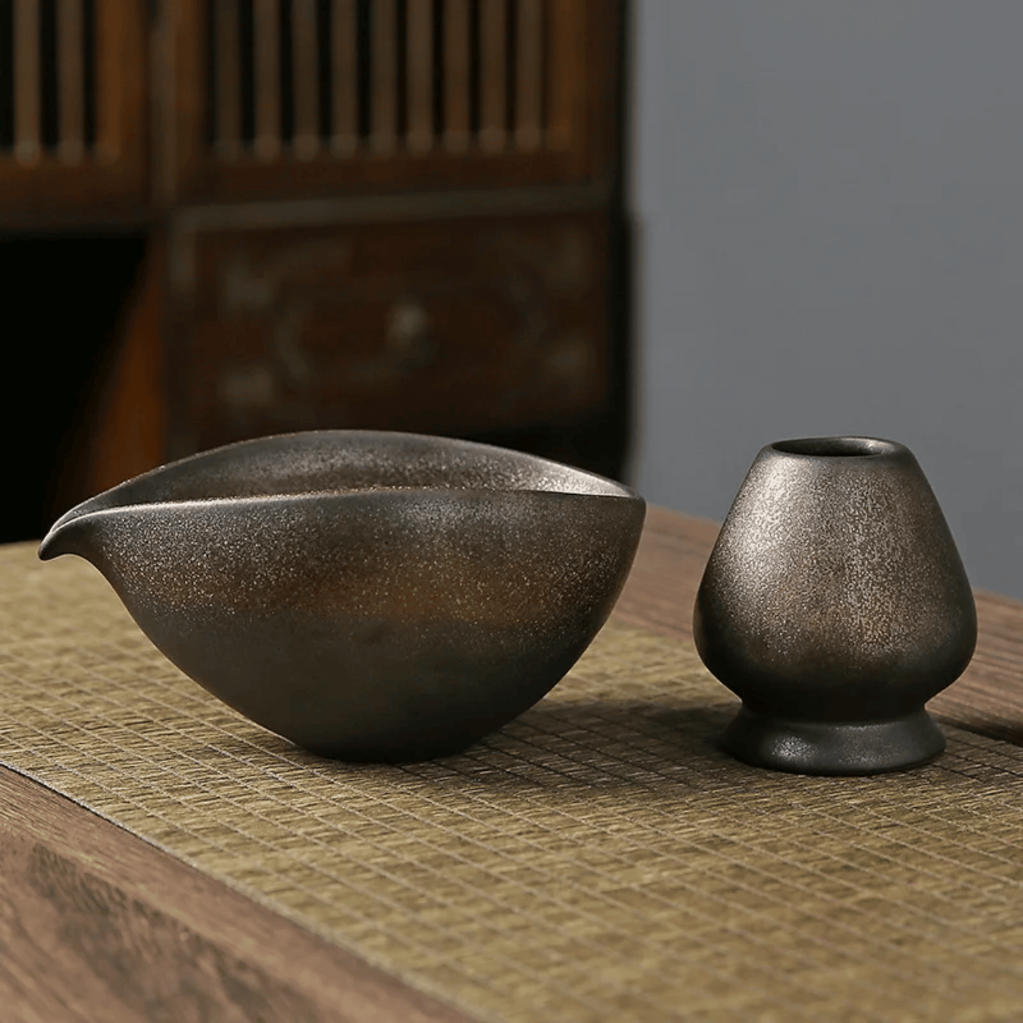 Two dark ceramic bowls on a textured surface with a blurred background