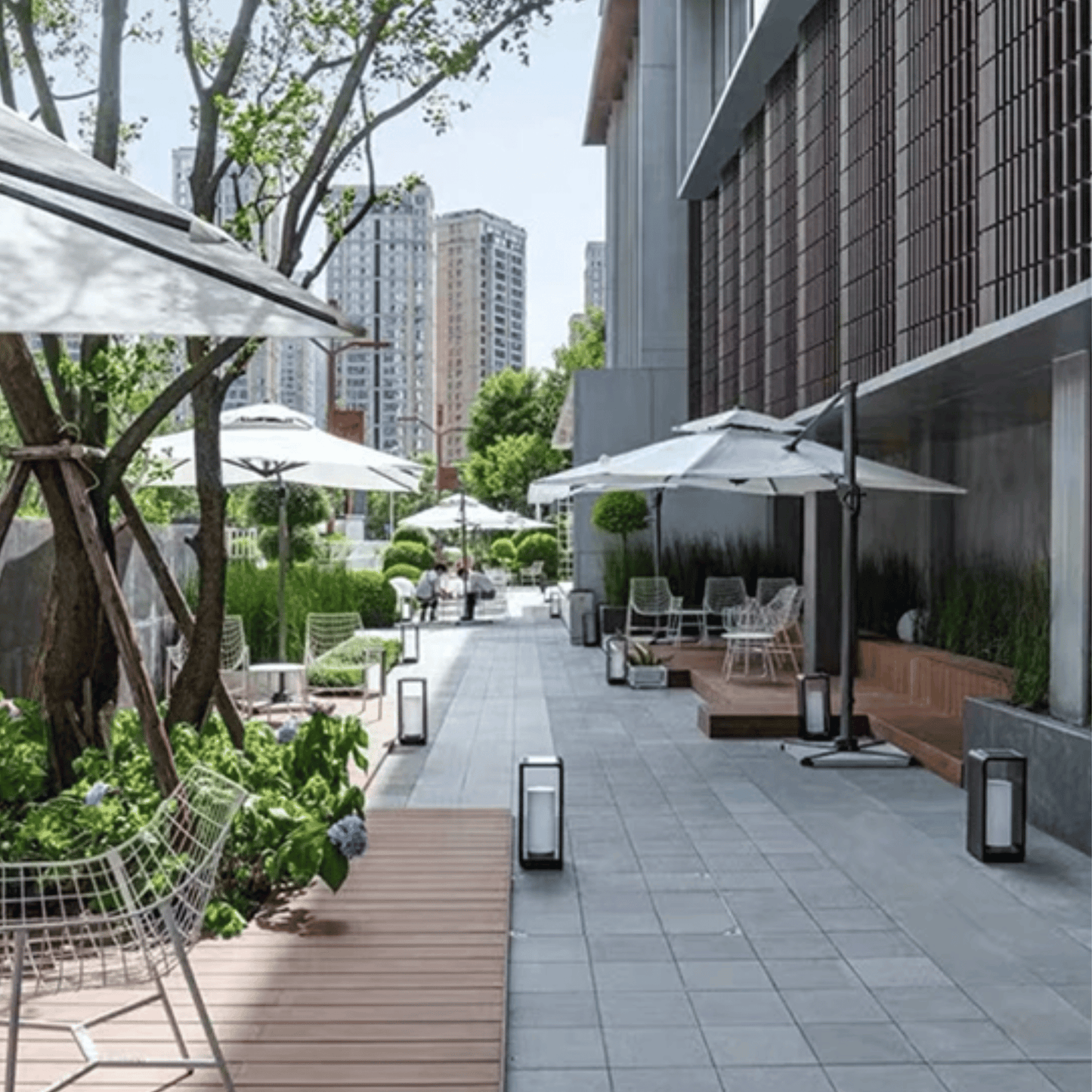 Outdoor patio area with tables, chairs, and umbrellas in an urban setting.